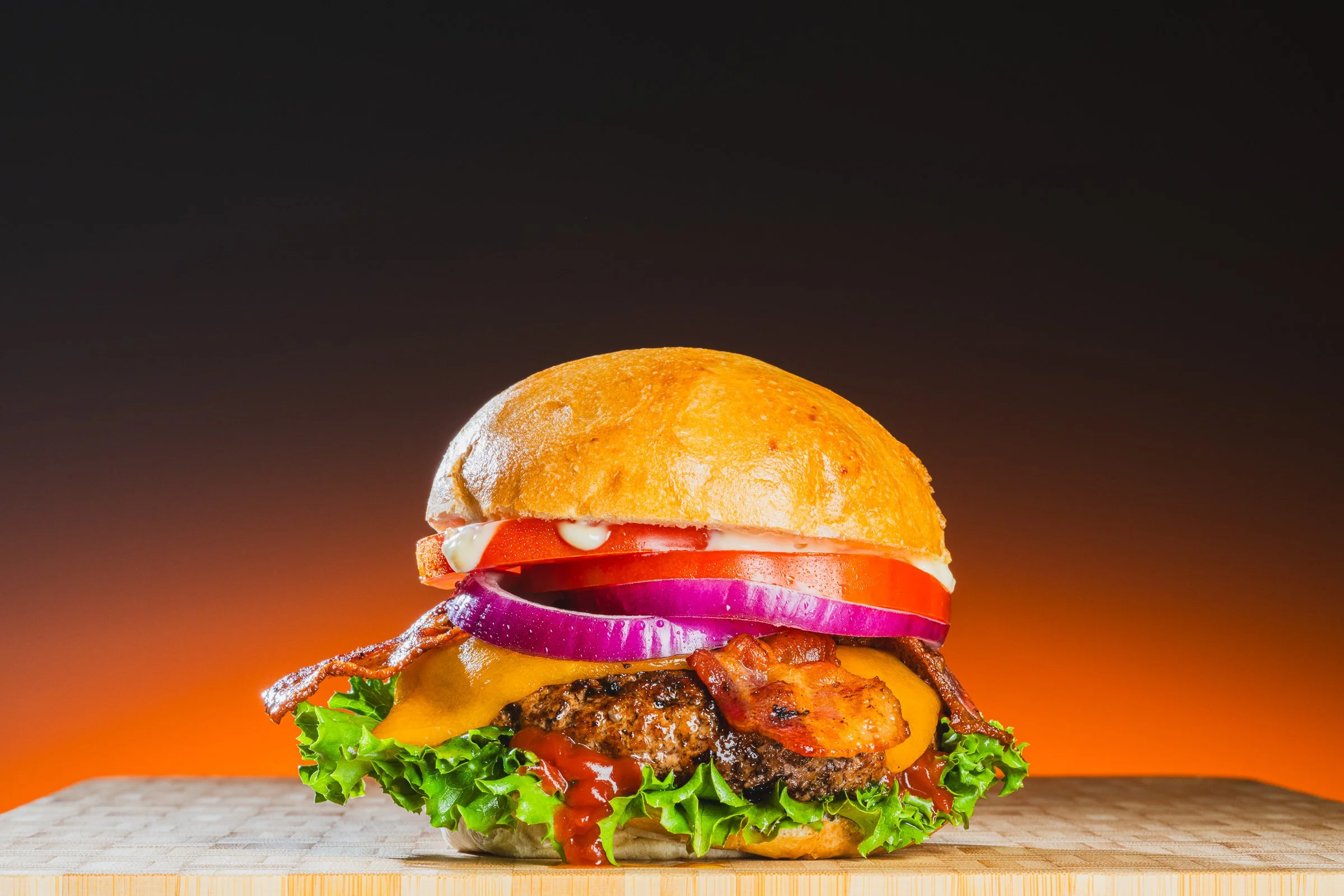 Gourmet hamburger with lettuce, tomato, onion, and cheese on a toasted bun.