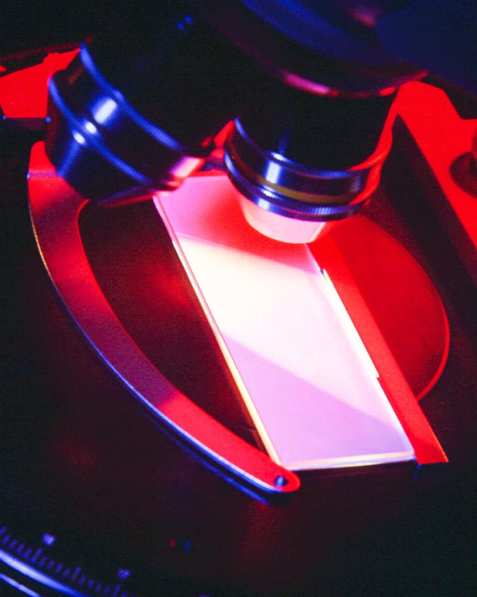 Close-up of industrial or laboratory equipment illuminated with red and blue light.