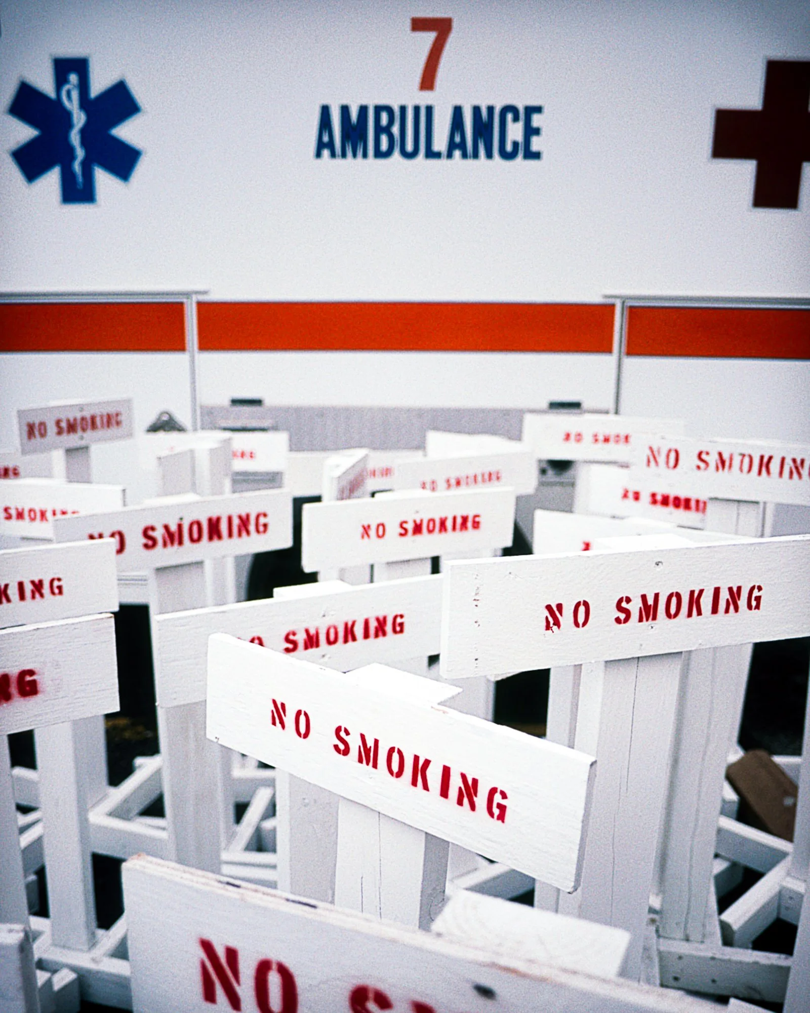 Stacked No Smoking signs next to ambulance