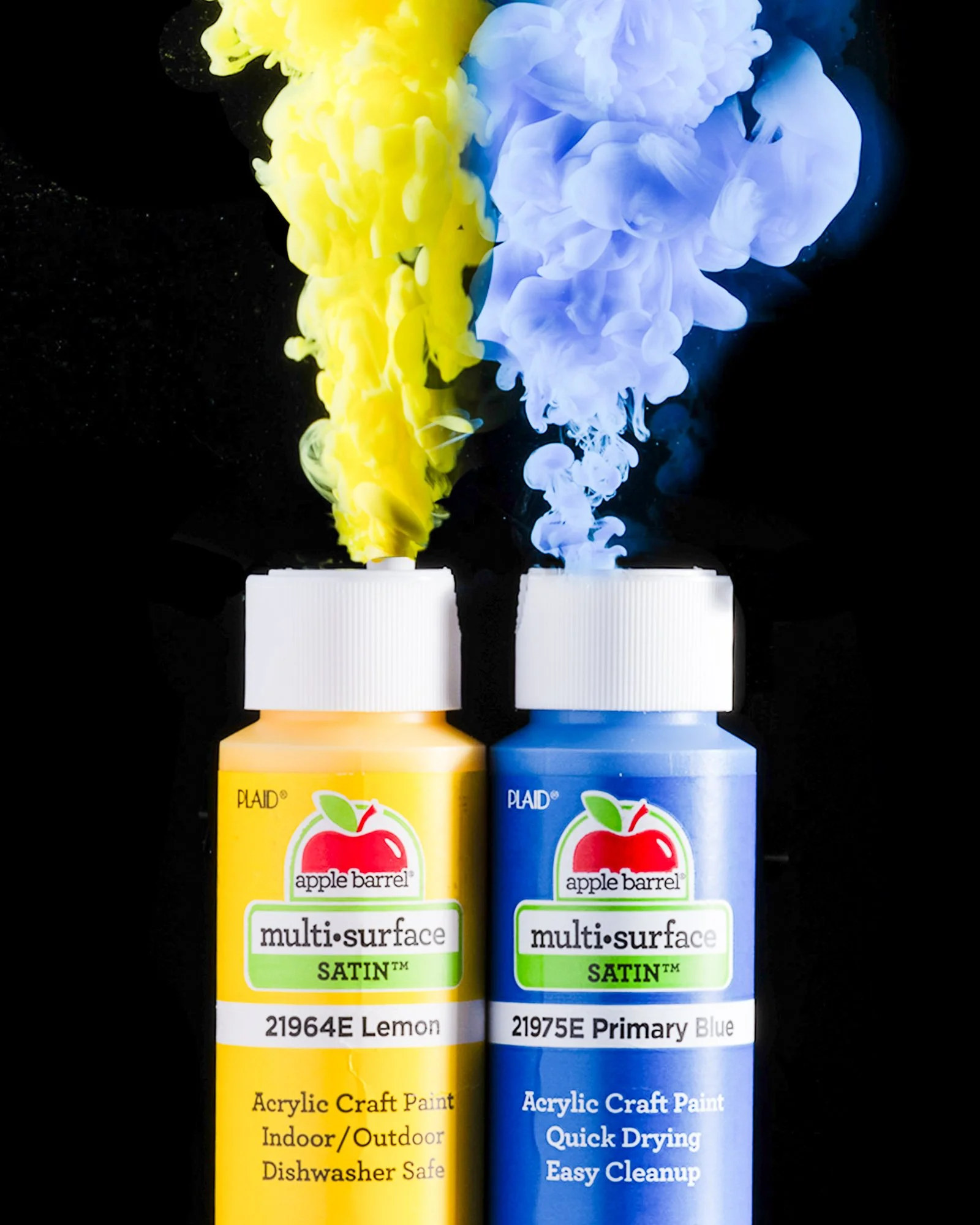 Two colorful paint bottles photographed with rising clouds of paint.