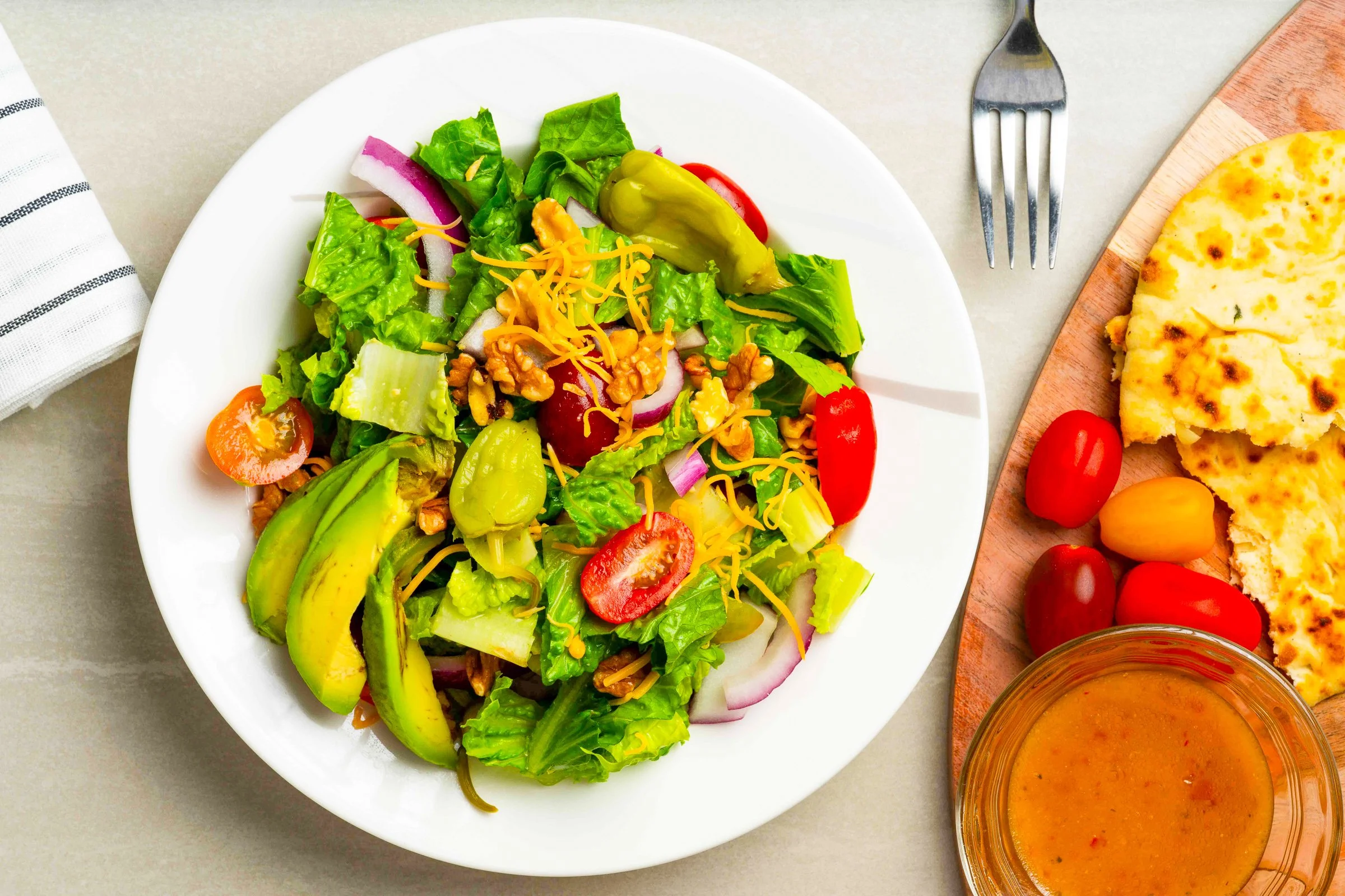 Fresh mixed salad served on a white plate with colorful vegetables.