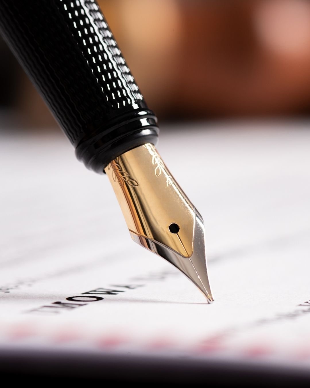 Close-up of a fountain pen writing on a white paper surface.
