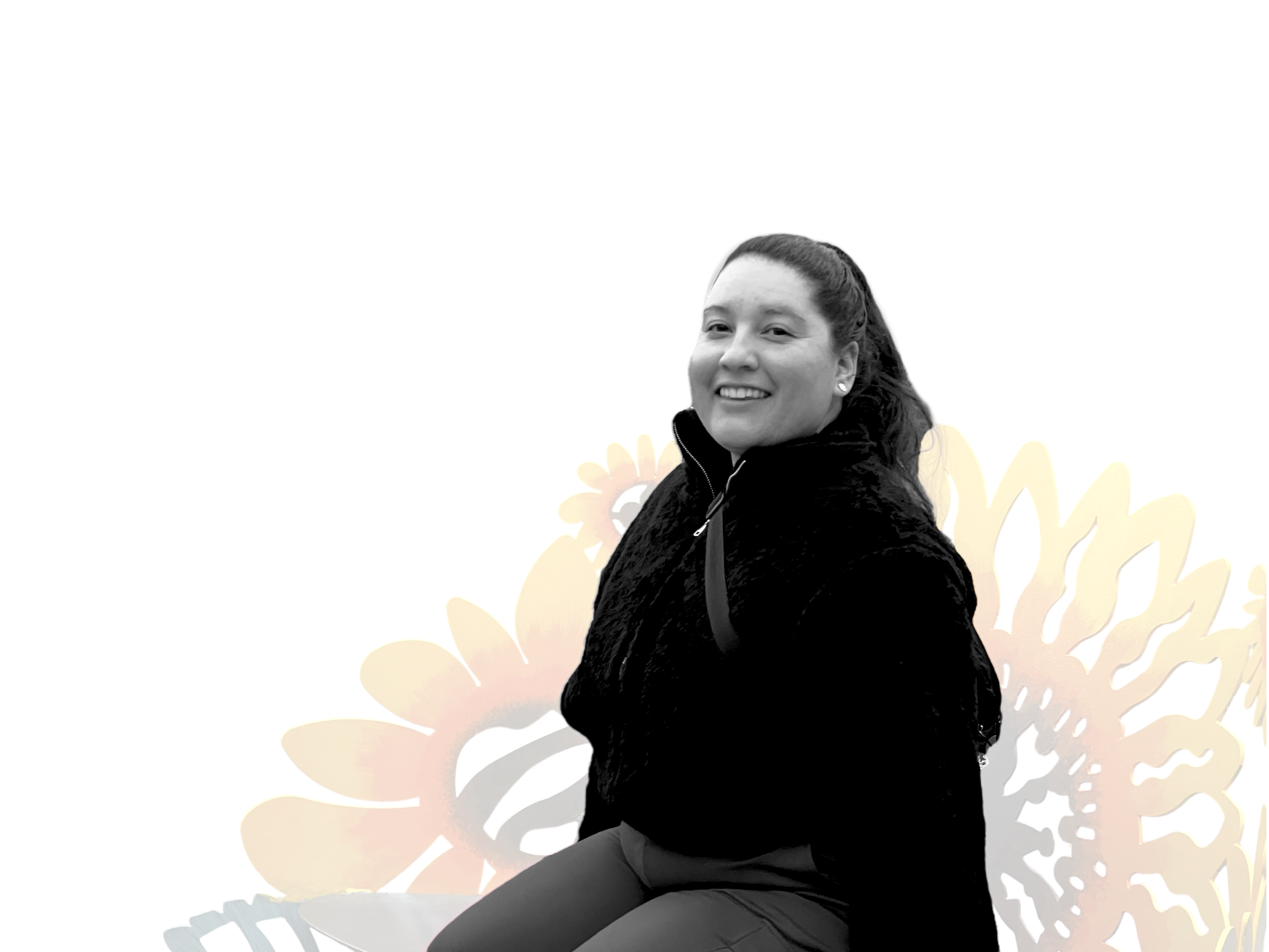 A woman smiling and sitting with a background of yellow and orange leaf-shaped decorations.
