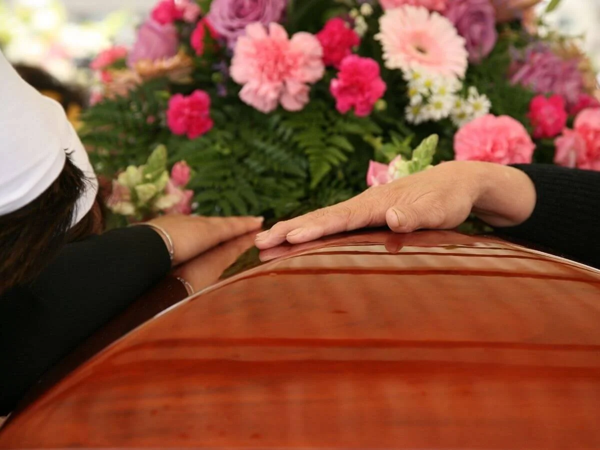 Loved Ones Touching a Casket at a Funeral