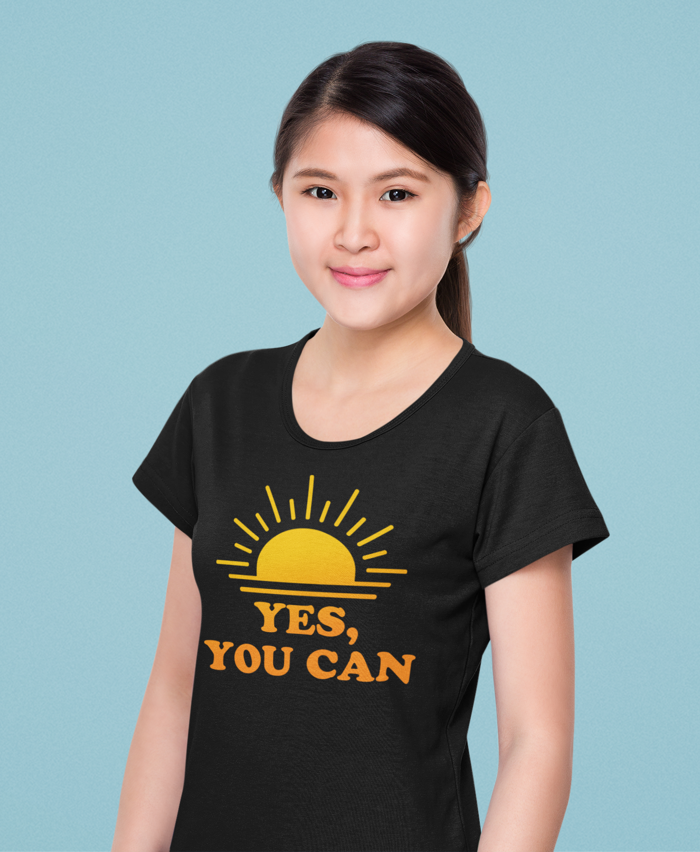 Young woman in black ‘Yes, You Can’ T-shirt with yellow sun graphic, smiling confidently — motivational fashion by E.N.K. Feel Good Apparel.