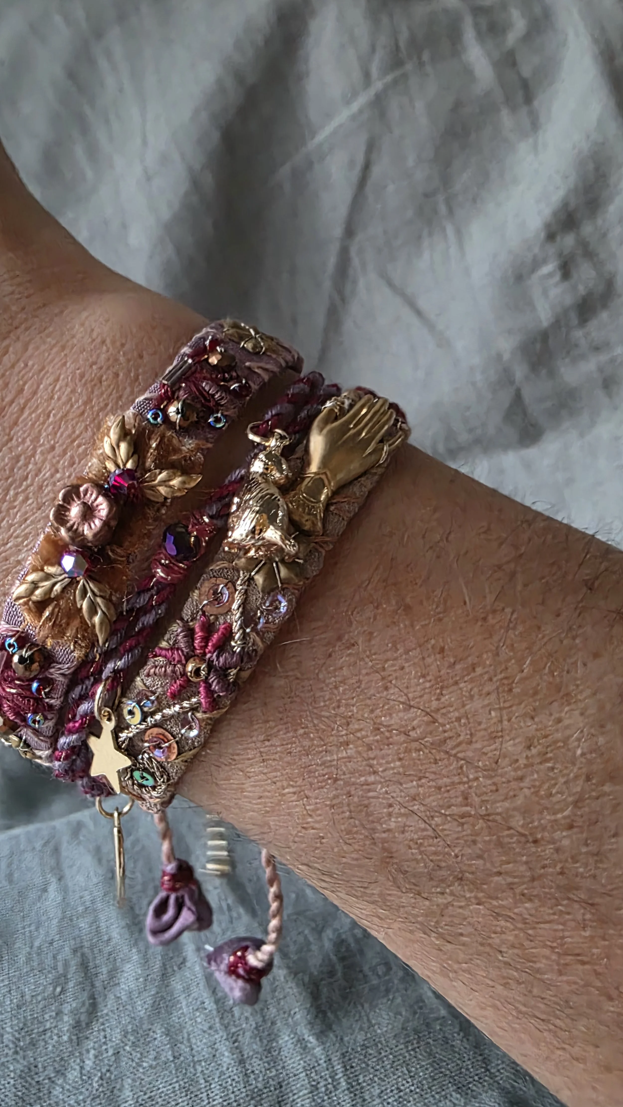 Two embroidered silk bracelets in magenta and gold shown on a wrist