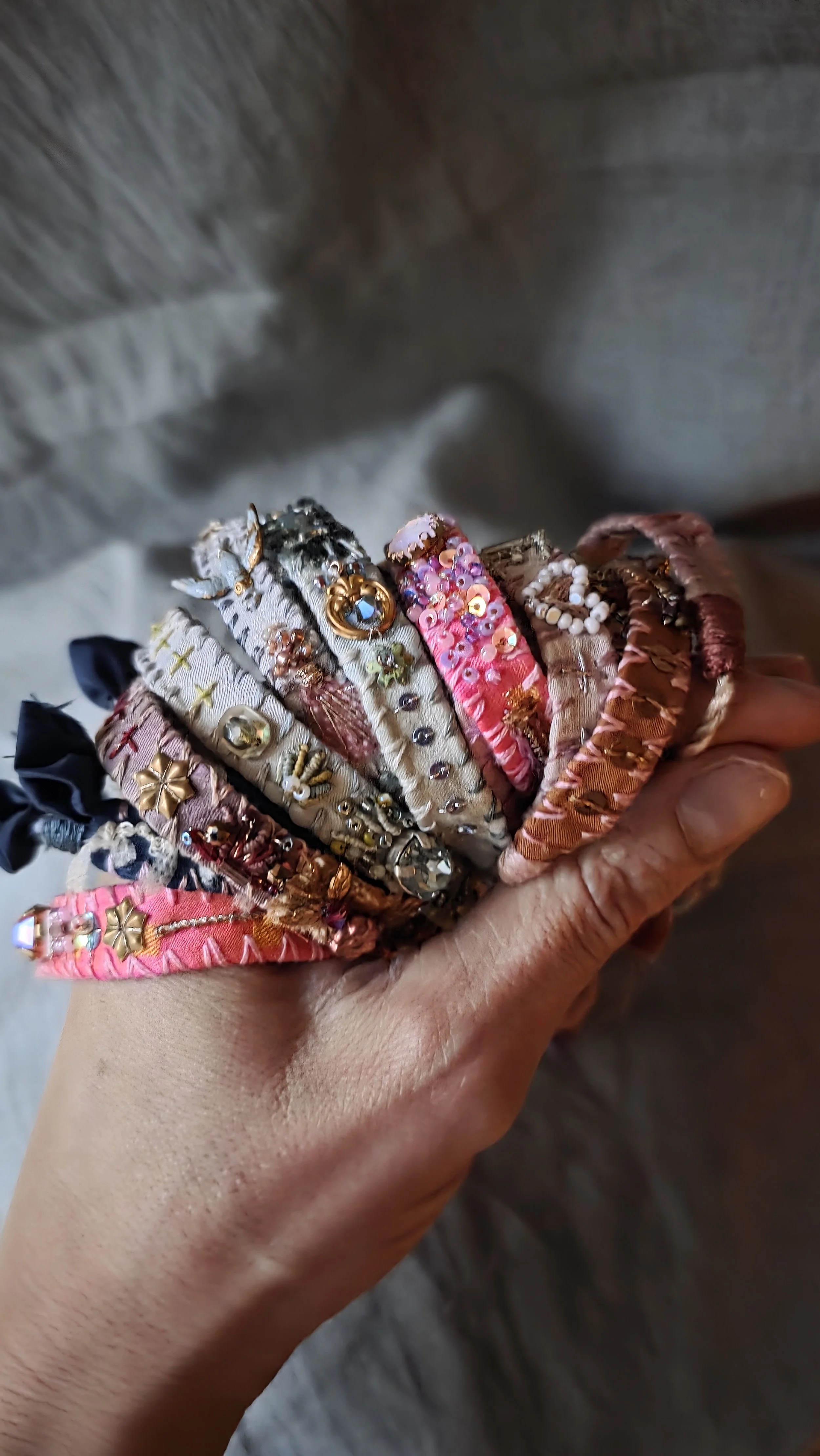 A collection of embroidered silk bracelets being held together