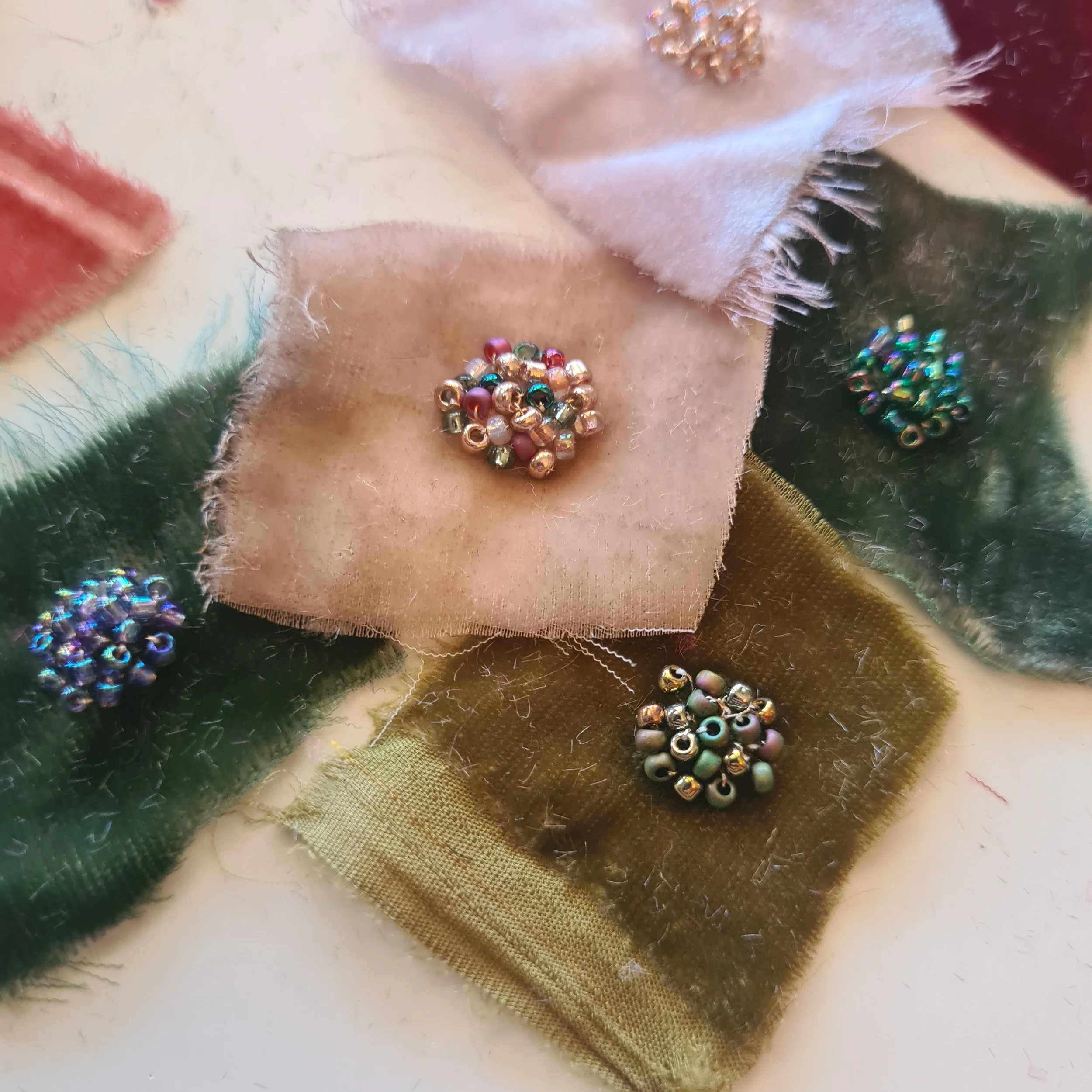 Colourful hand-dyed velvet fabric swatches embellished with pearls and beads.