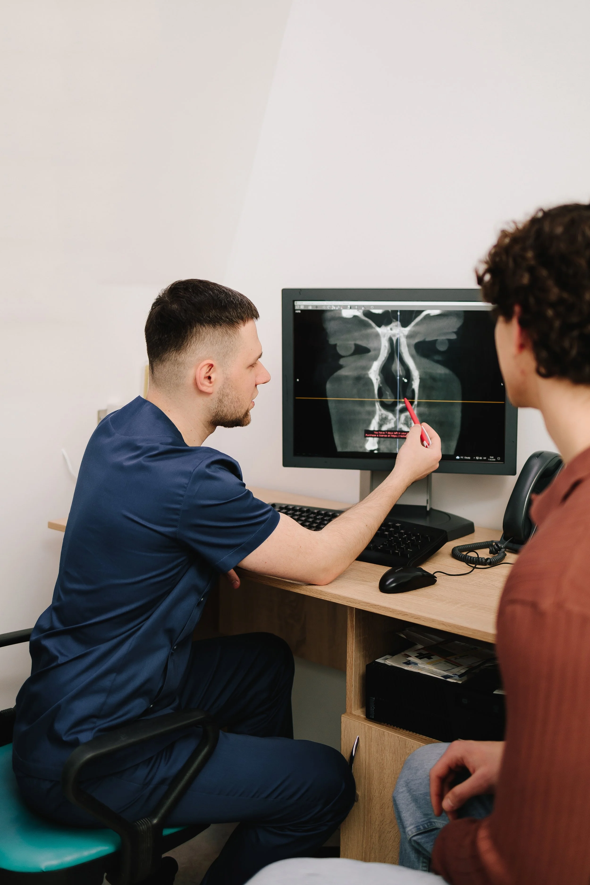 A doctor explaining a nasal X-ray to a patient in an office.