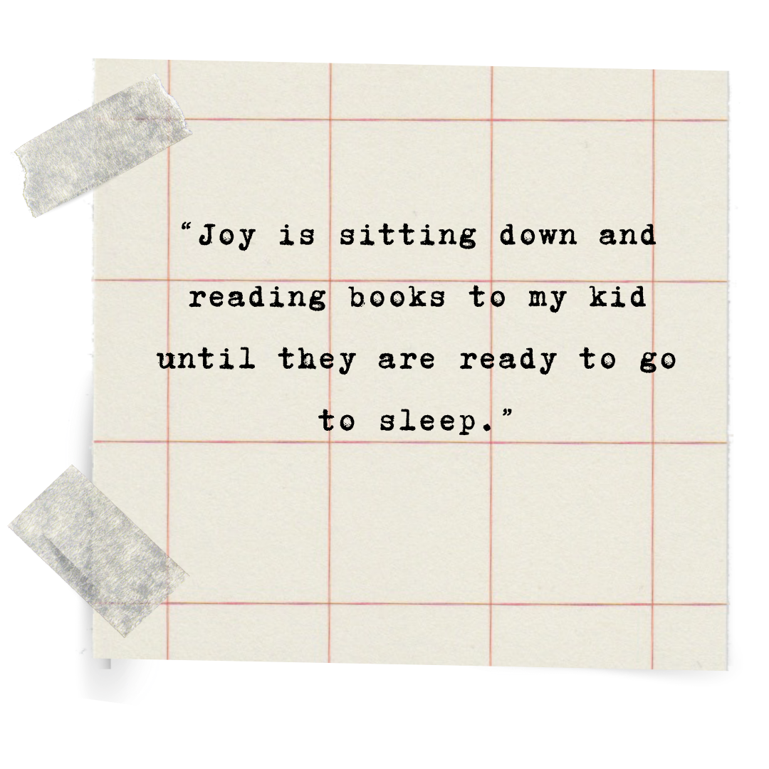 A piece of grid paper with a quote typed in black ink that reads, 'Joy is sitting down and reading books to my kid until they are ready to go to sleep.' The paper is taped with silver tape on the corners.