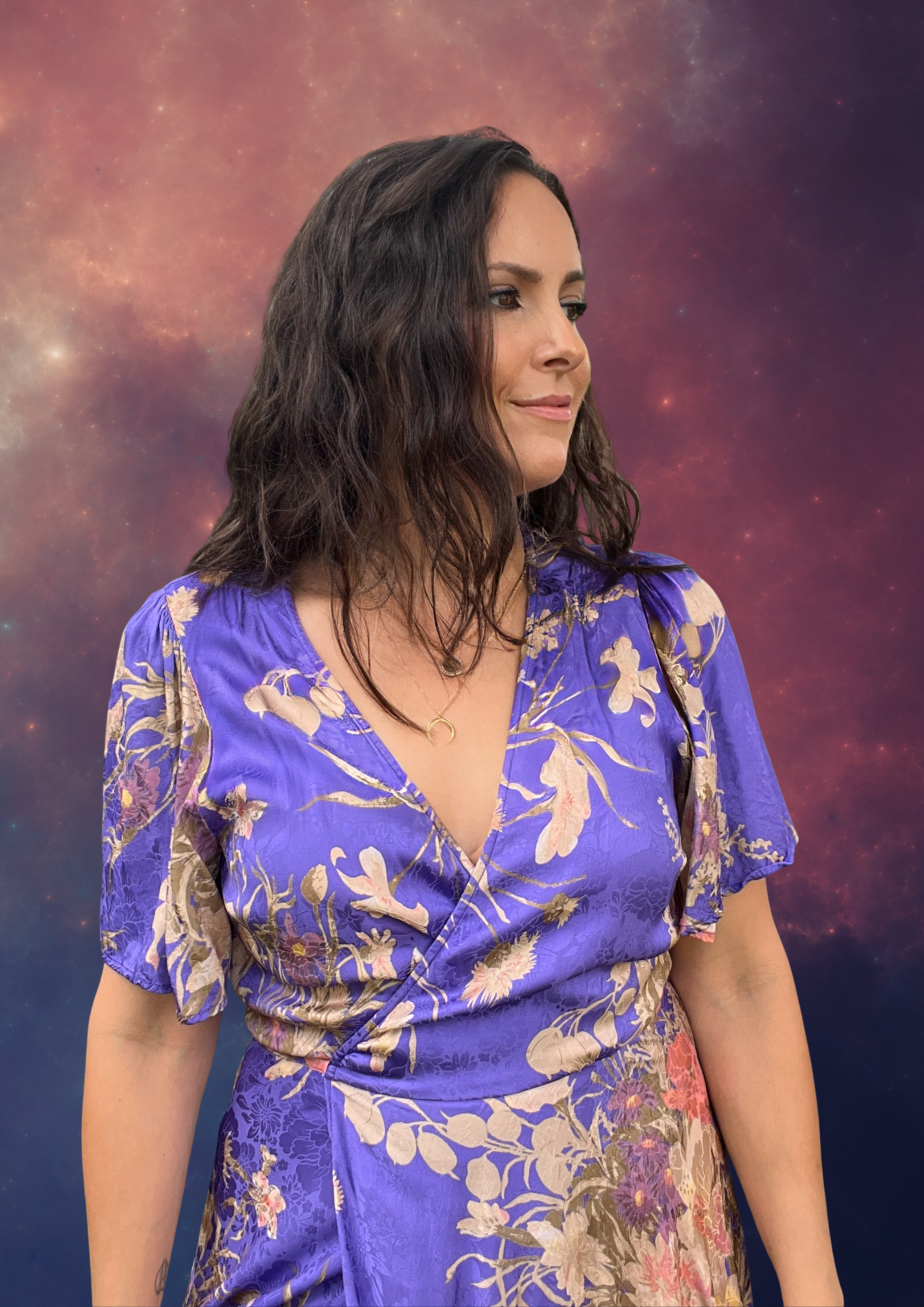 A woman with dark wavy hair wearing a purple floral dress, standing against a cosmic background with stars and nebulae.