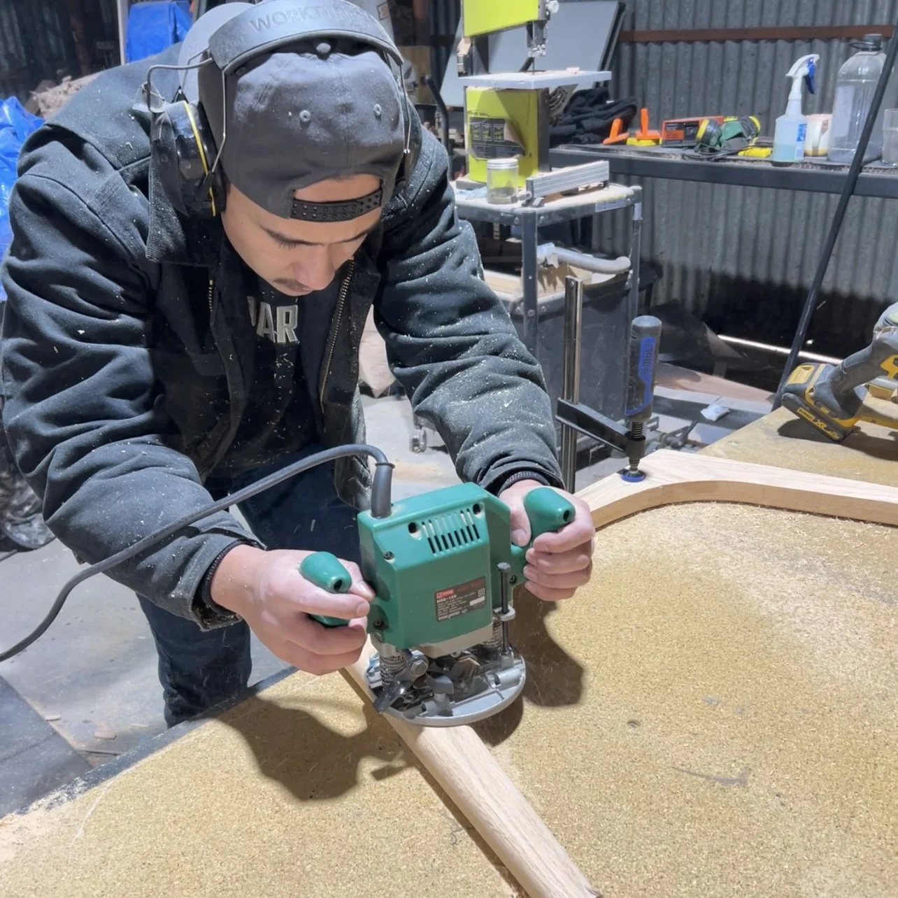 A person using a handheld power tool to carve or cut a piece of wood in a workshop.