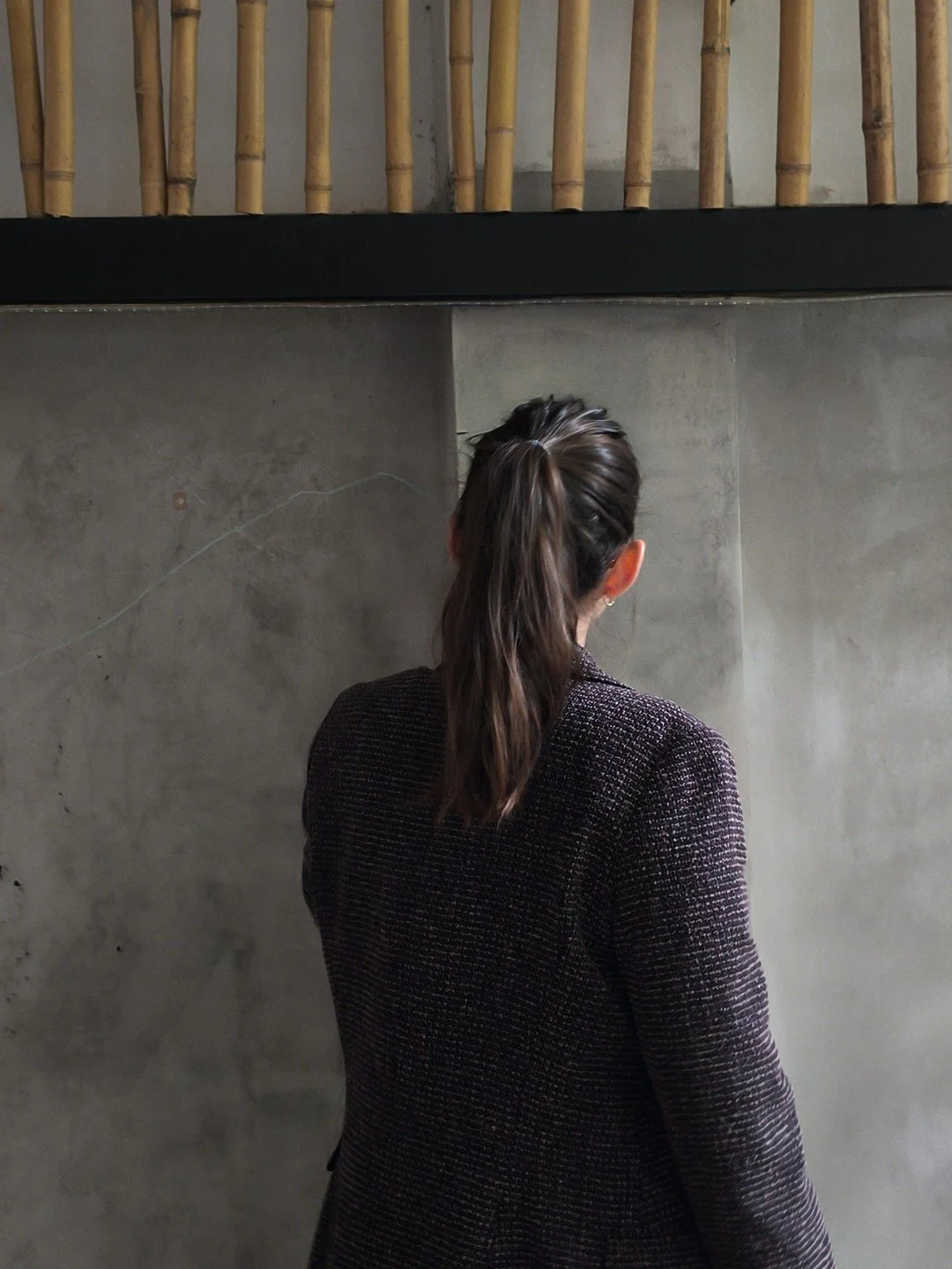 Mujer con cabello recogido viendo una pared de concreto en un espacio moderno.