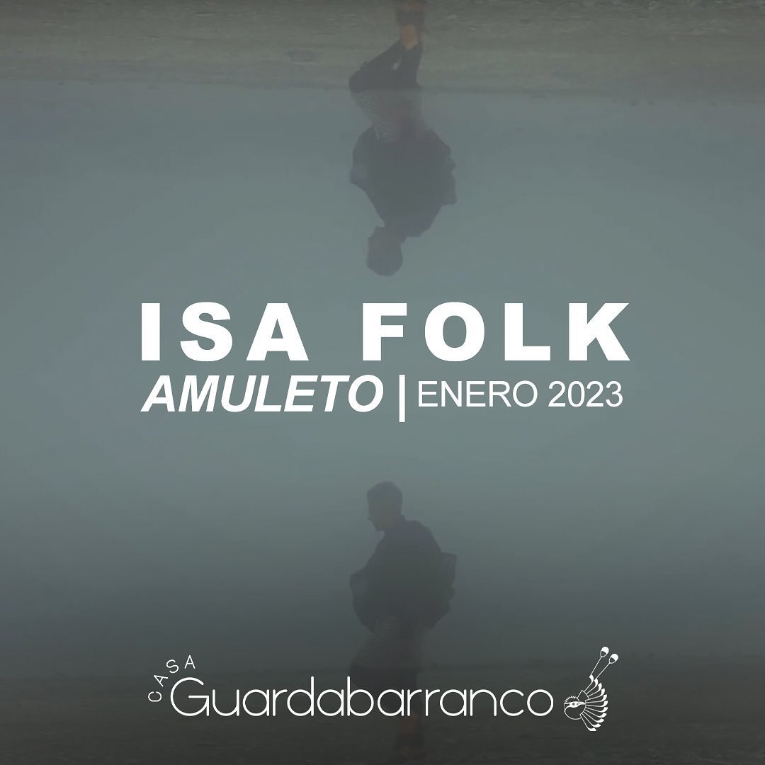 Página promocional con reflejo de una persona en agua. Texto que dice "Isa Folk Amuleto Enero 2023" y en la esquina inferior izquierda "Casa Guardabarranco" con un símbolo de un guardabarranco.