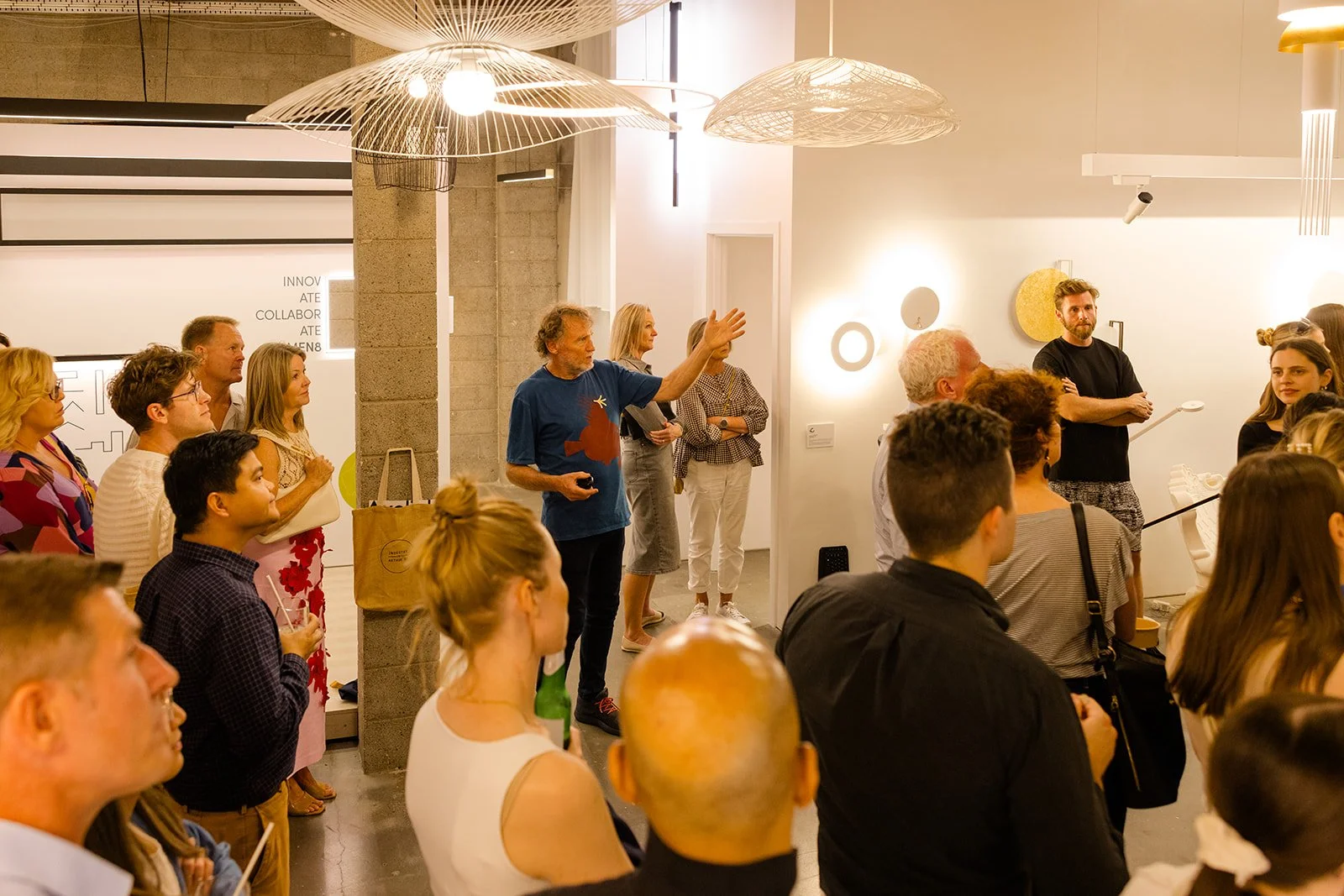 A group of people attending a presentation or lecture in an indoor space with modern lighting and decor.