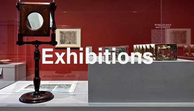 Museum exhibit with antique clock, framed pictures, and art pieces displayed under glass