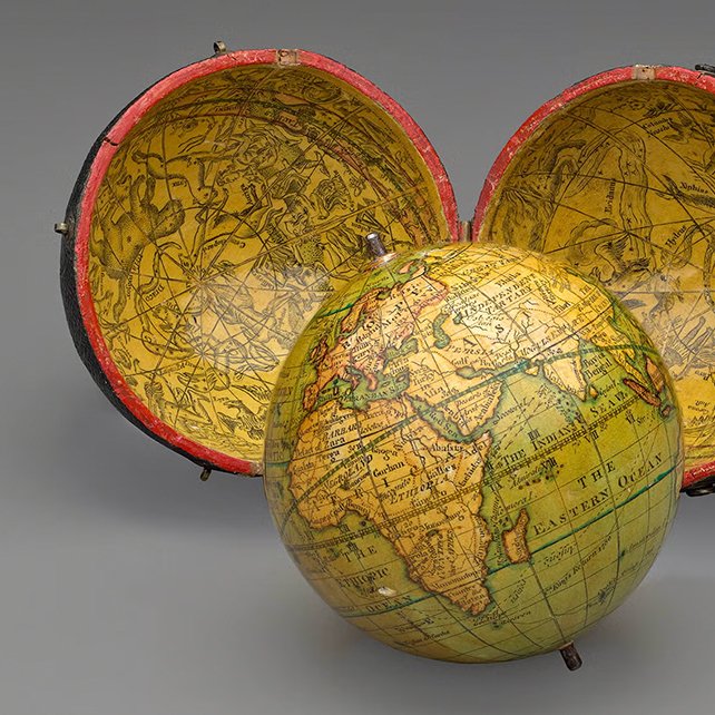 A vintage globe inside a decorative case with a celestial map, opened to show Africa and surrounding continents.