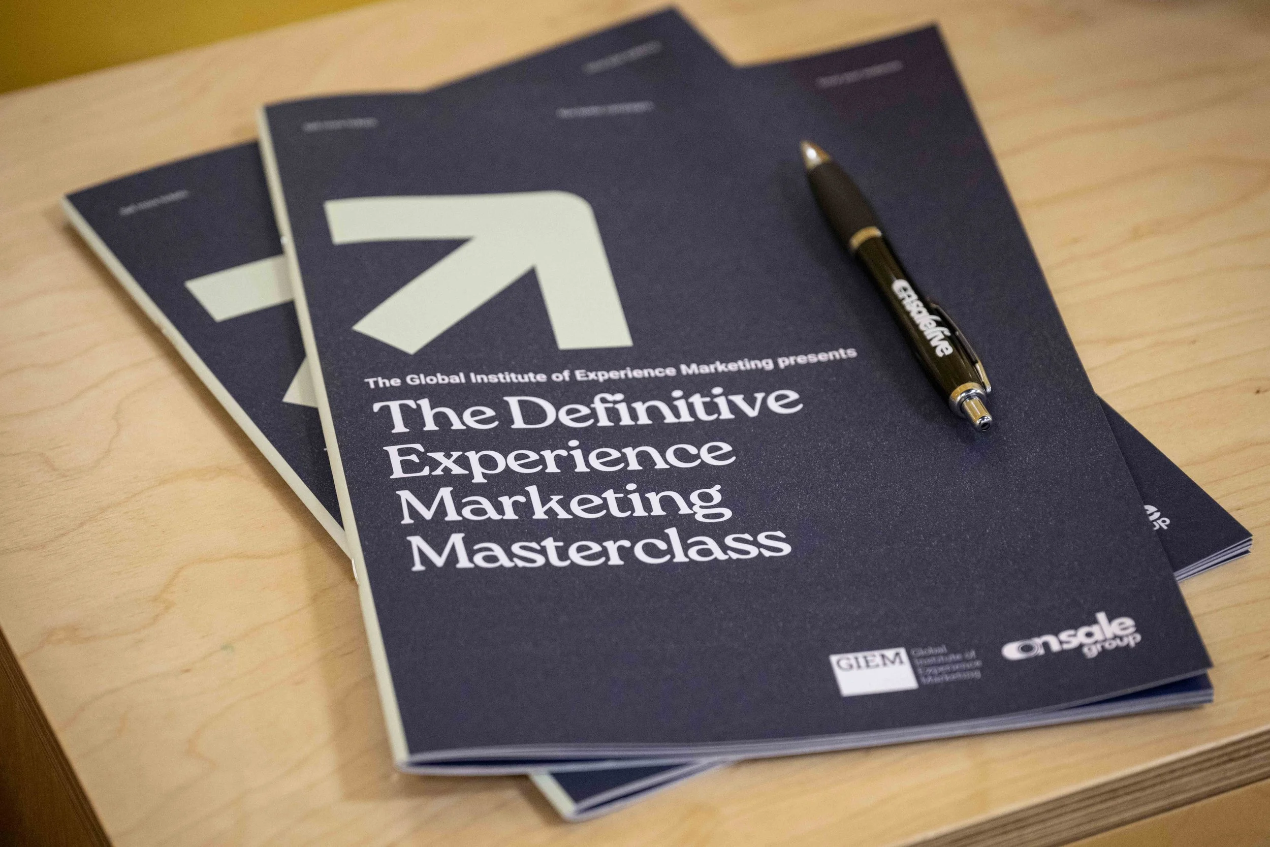 Several printed syllabus booklets titled 'The Definitive Experience Marketing Masterclass' with On Sale Live pens