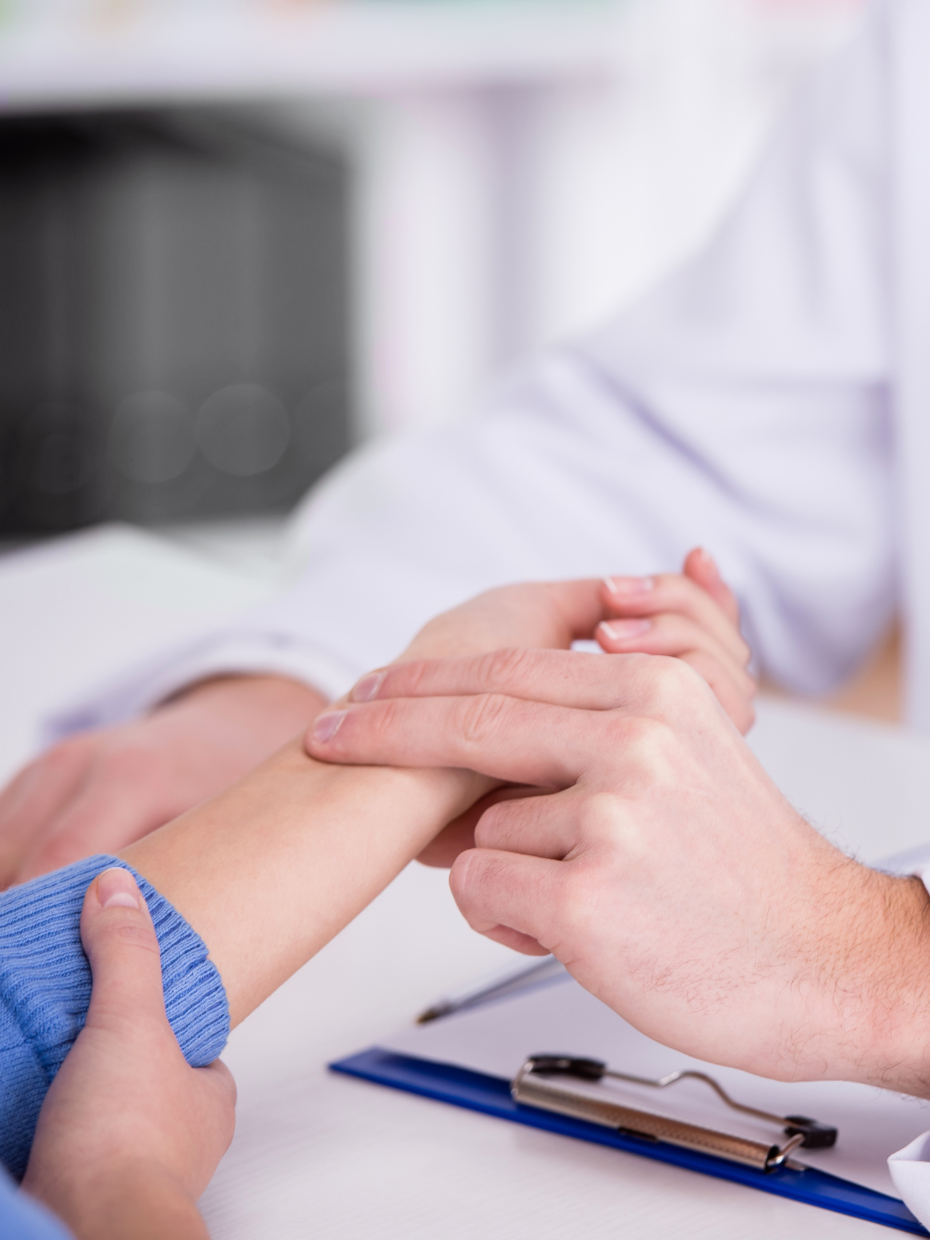 A healthcare professional holding a child's arm during a medical examination or treatment.