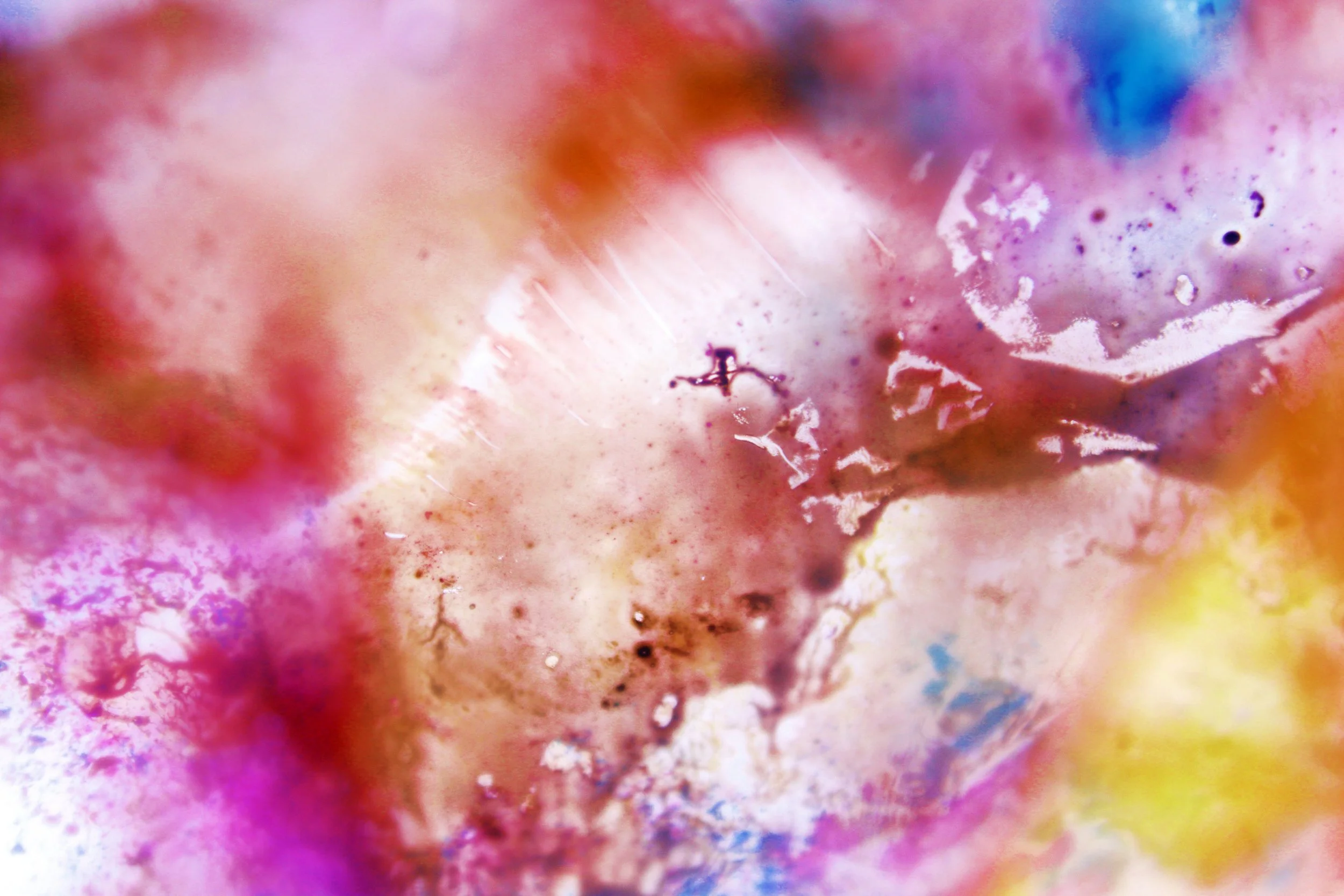 Close-up of a colorful, abstract, watercolor-like painting with pink, purple, yellow, and blue hues blending together.