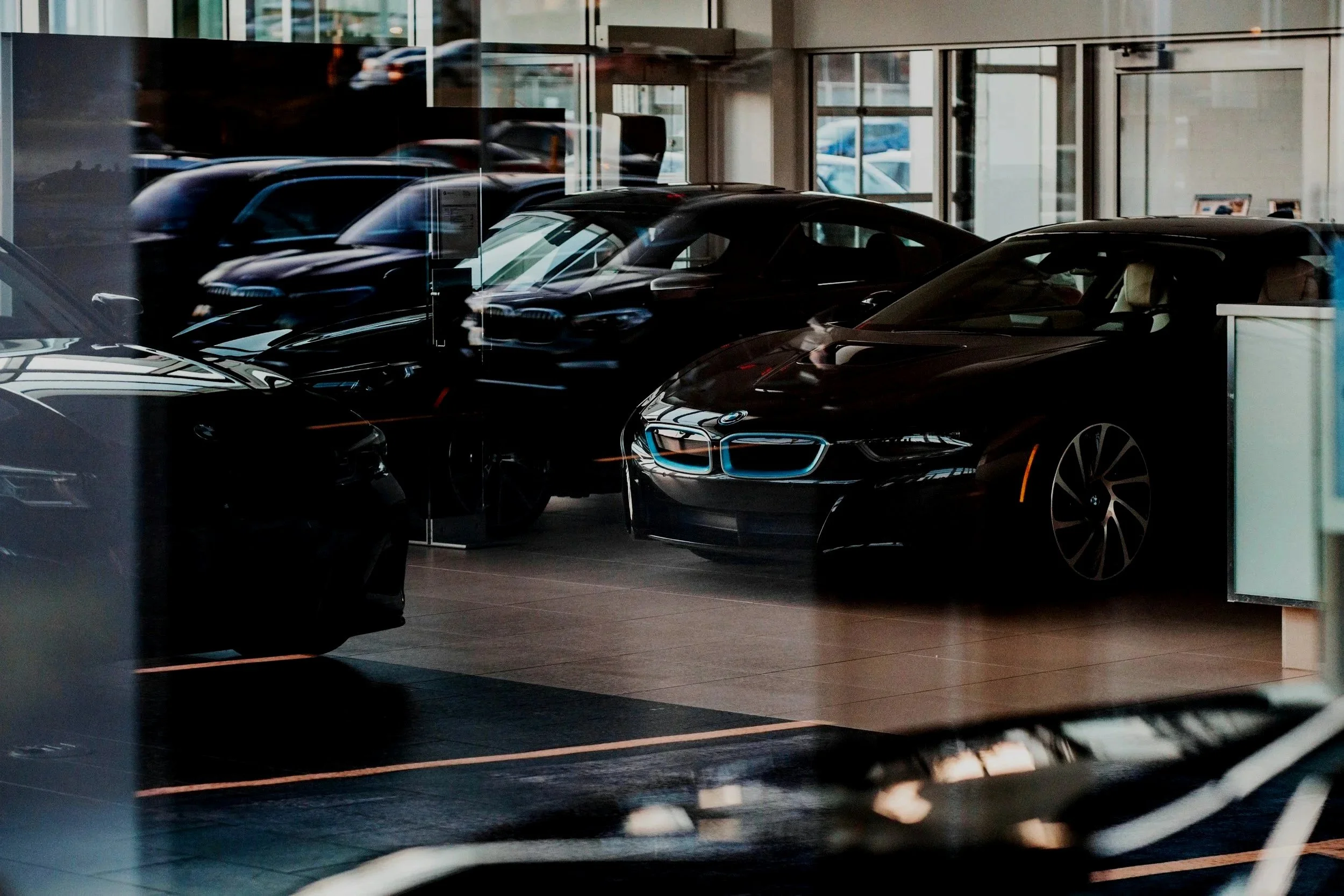 Several black electric cars on display inside a car dealership with large windows.