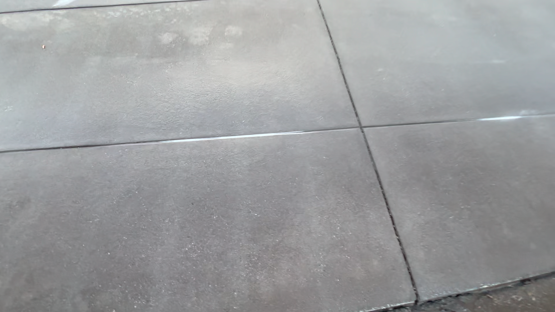 Close-up of a tiled floor with large gray tiles and visible grout lines.