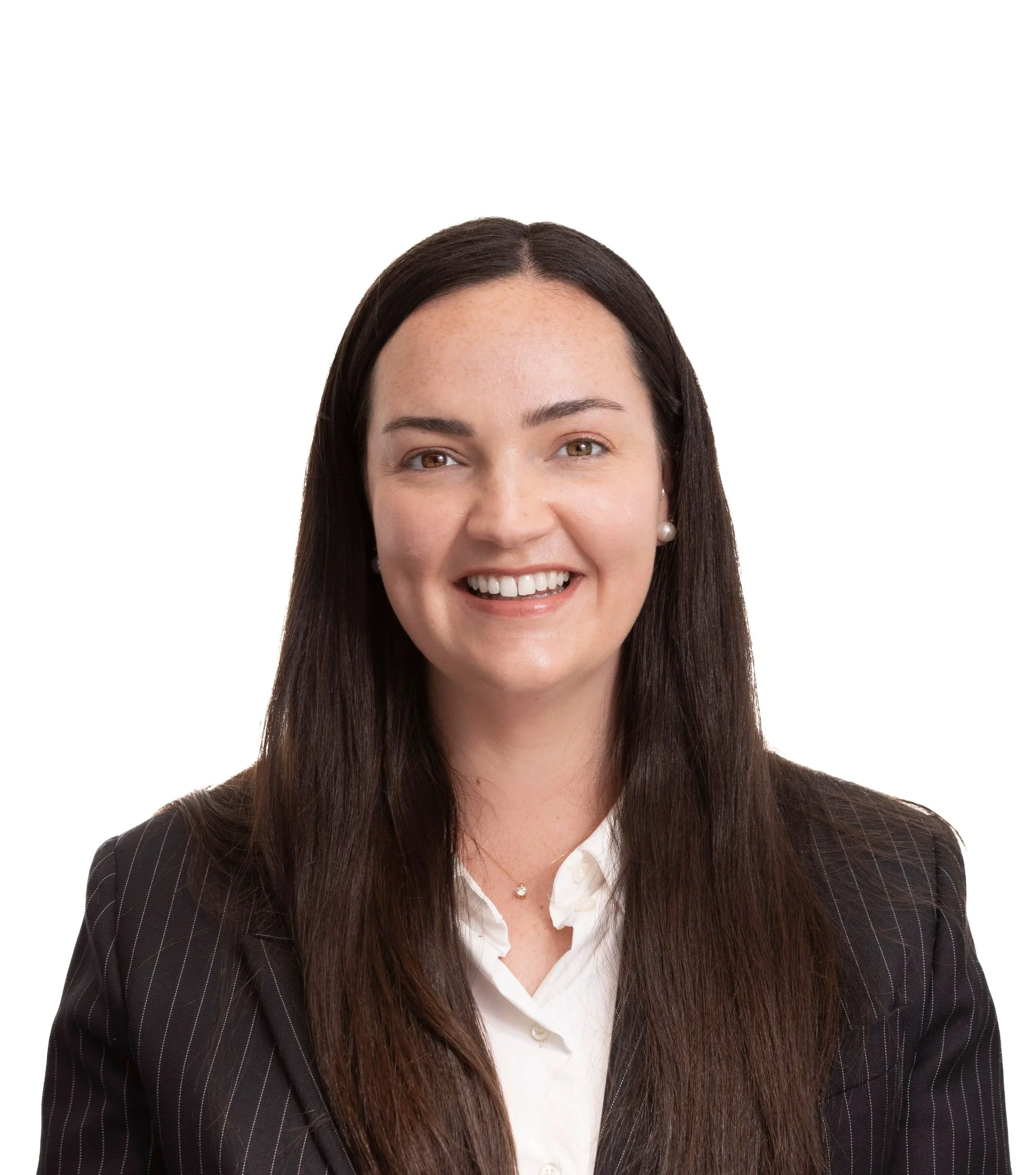Headshot of a woman with long dark hair, wearing a dark blazer, white blouse, pearl earrings, smiling in front of a white background.
