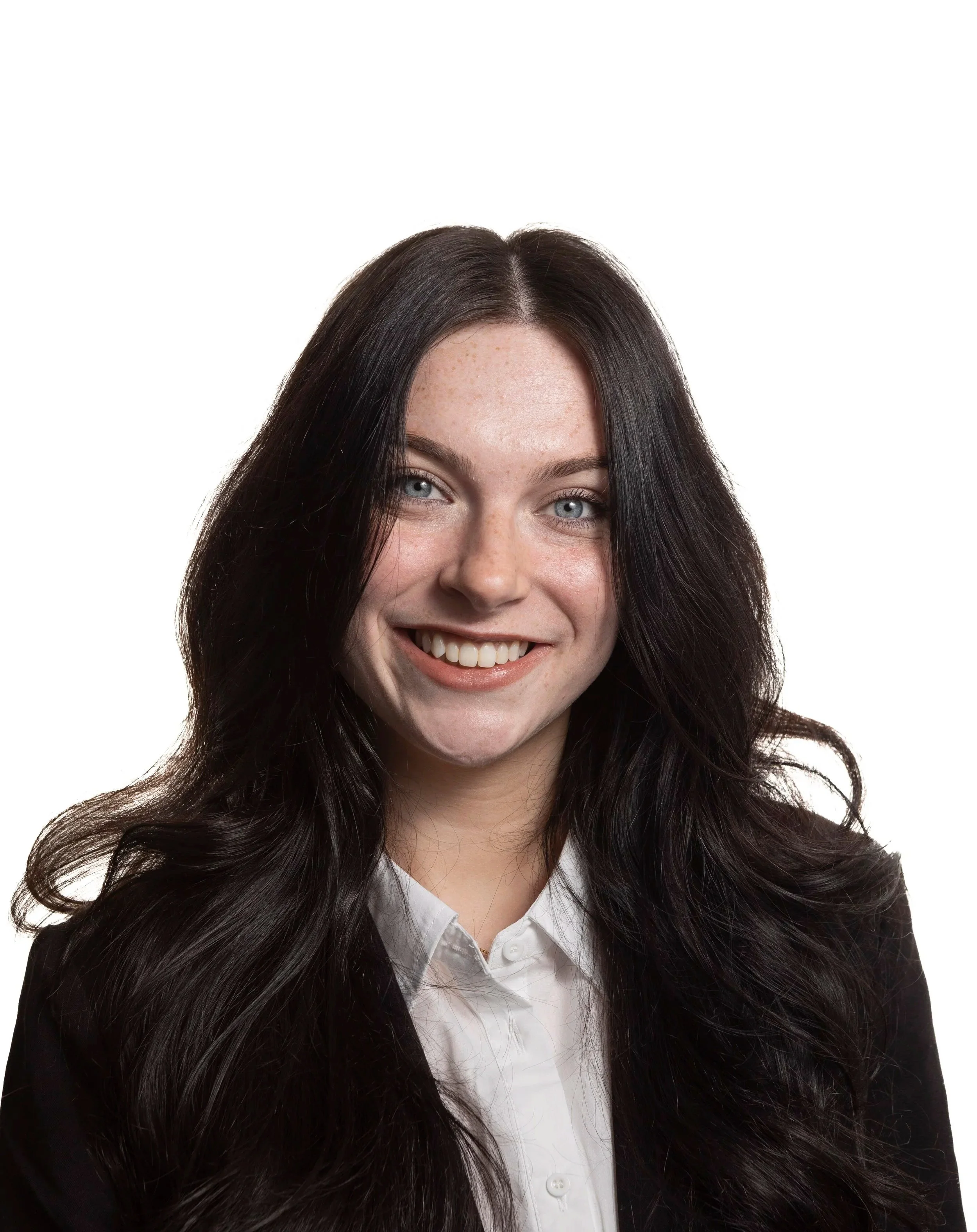 A young woman with long dark hair, blue eyes, and light skin, smiling, wearing a white shirt and dark blazer, against a white background.