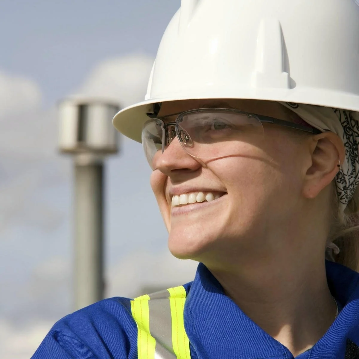 Happy female engineer wearing white helmet looking in the distance on site.jpg