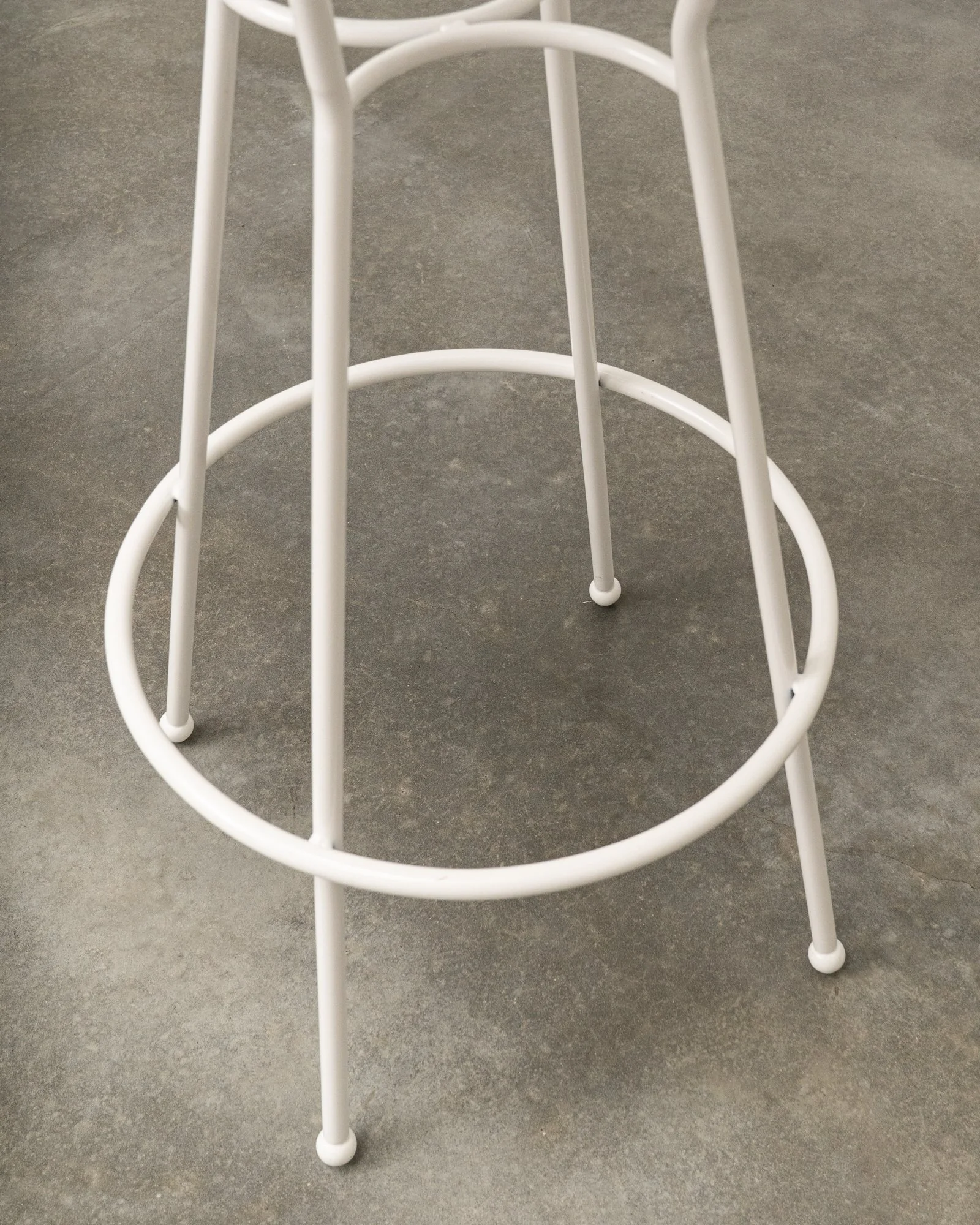 White metal ringed stool base on a gray concrete floor.