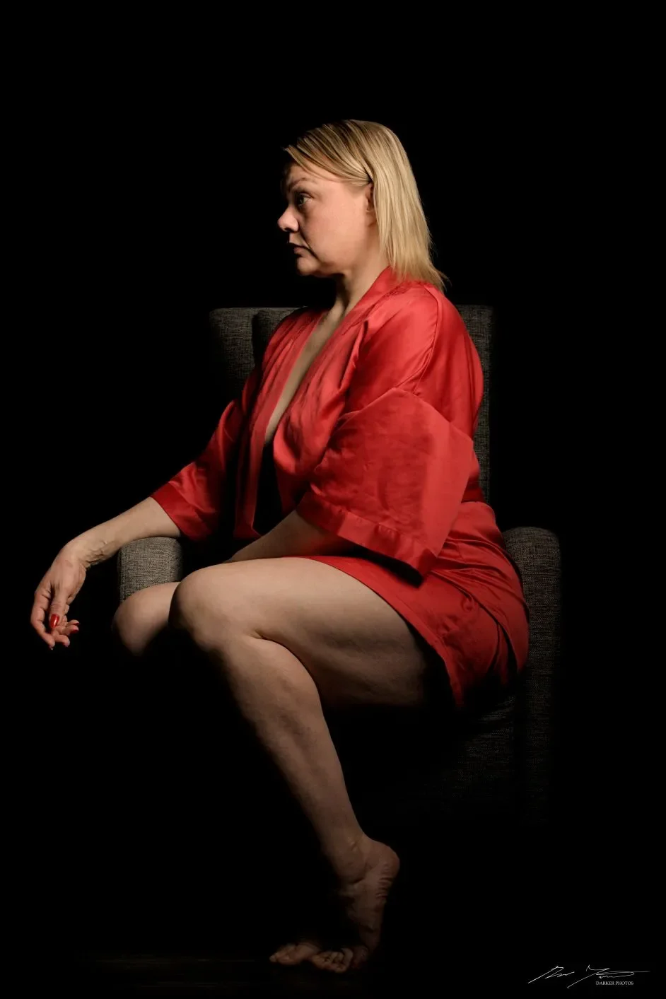 Nainen istuu tuolissa, pukeutuneena punaisiin asuun.