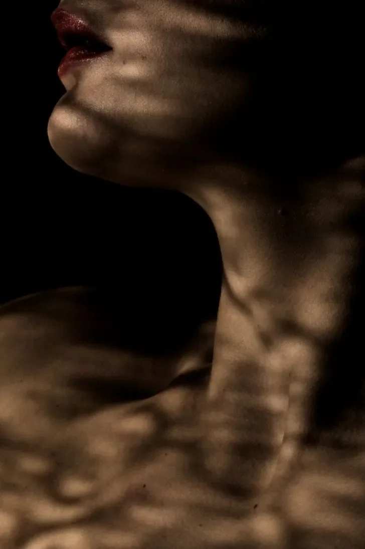 Lähikuva ihmisen leuasta ja suupielestä pimeässä ympäristössä.