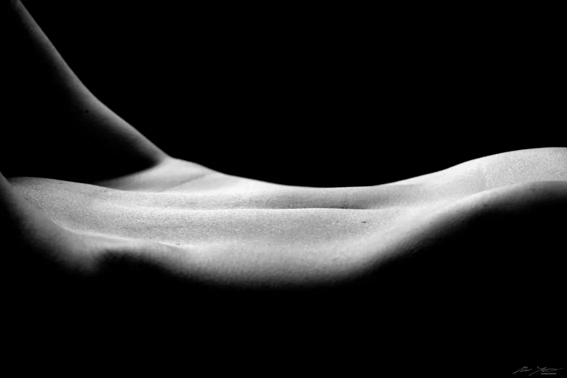 Taiteellinen, tummasävyinen lähikuva ihmisen vatsasta.