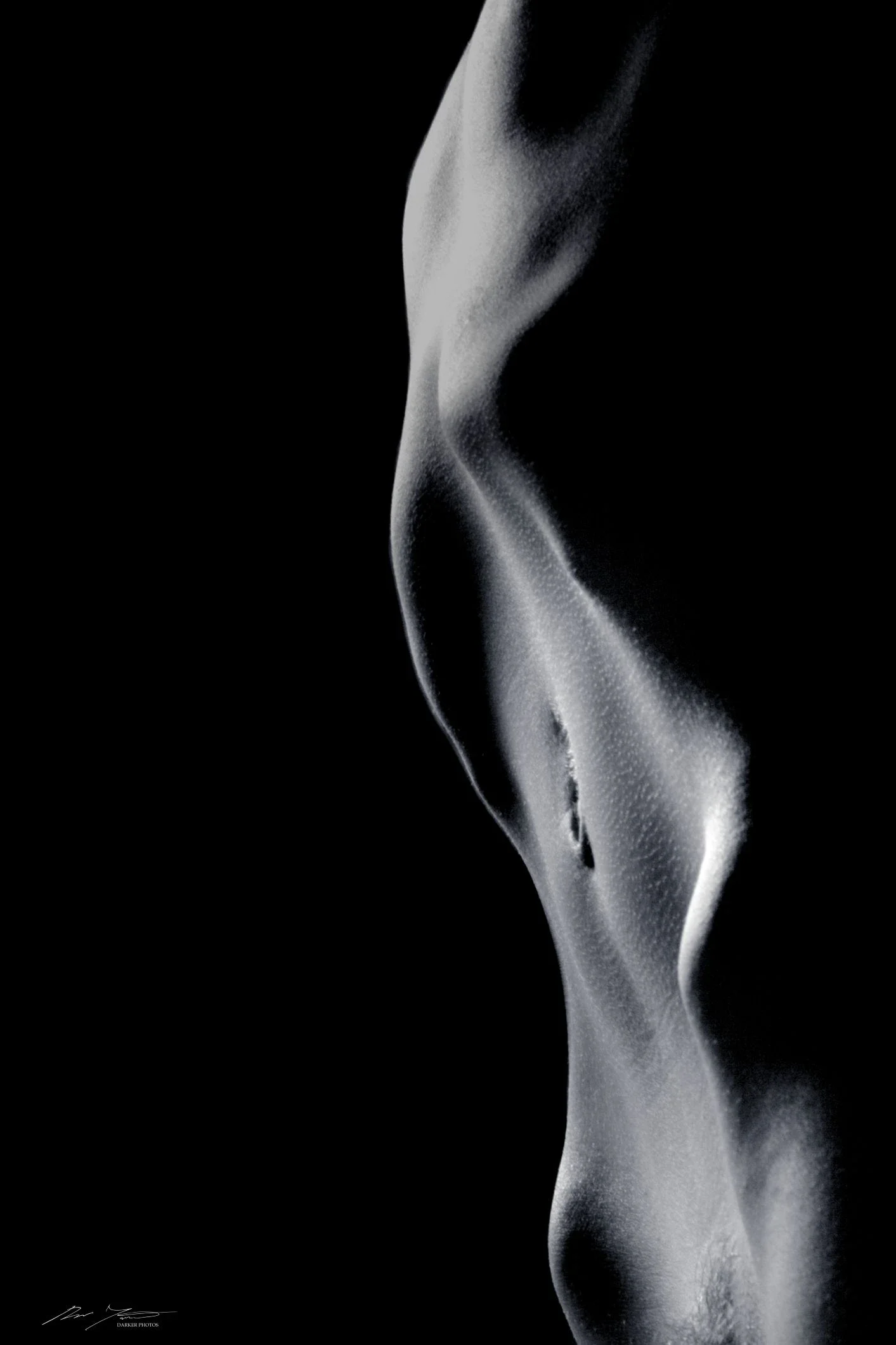 Mustavalkoinen, taiteellinen lähikuva vatsasta tummalla taustalla.