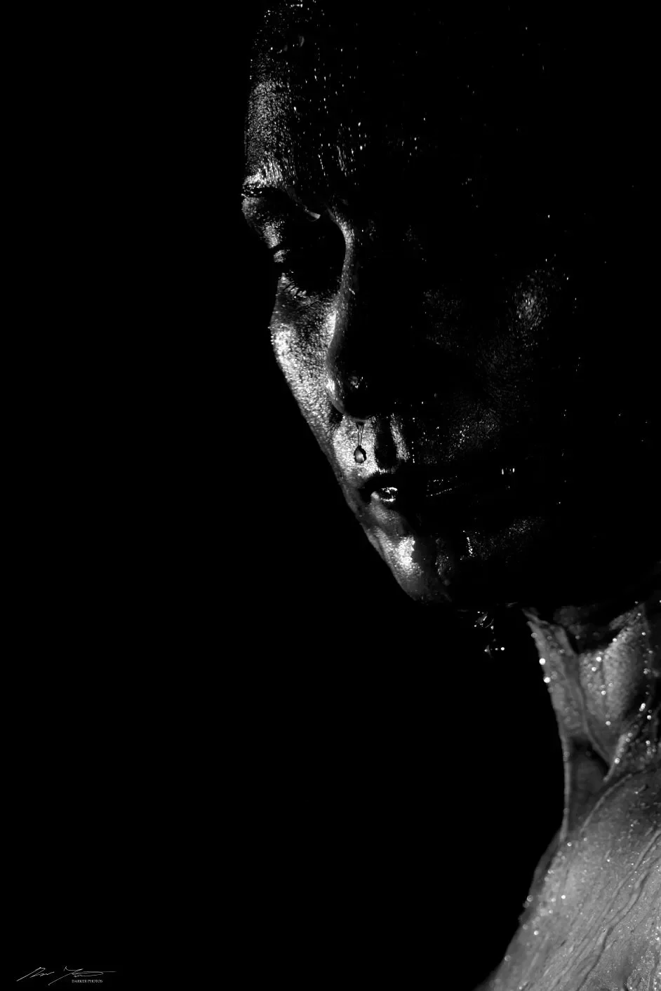 Tummasävyinen kuva, jossa henkilön kasvoille tulee hieman valoa.