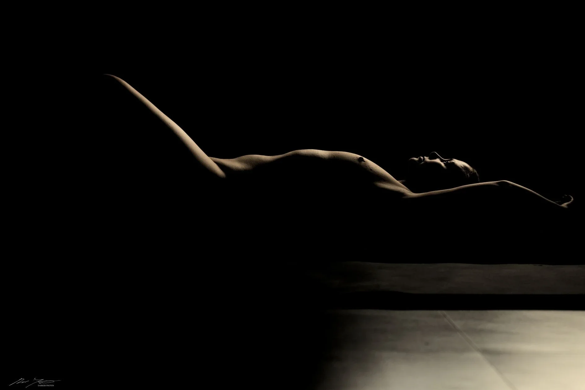 Henkilö makaa pimeässä, kehon piirteet näkyvät hämärästi. 