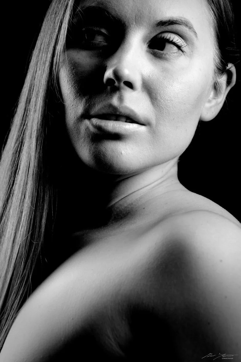 Harmaasävyinen kuva naisesta, joka katsoo sivulle, hiukset osittain kasvojen sivulla.