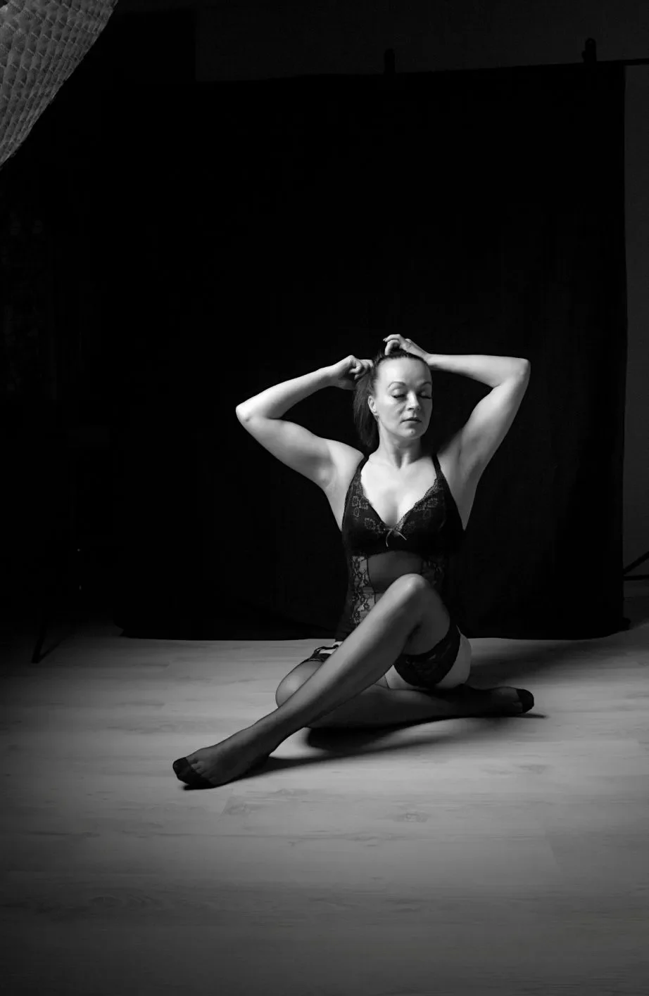 Mustavalkovalokuva naisesta, joka istuu lattialla polvet koukistettuna, kädet pään takana.