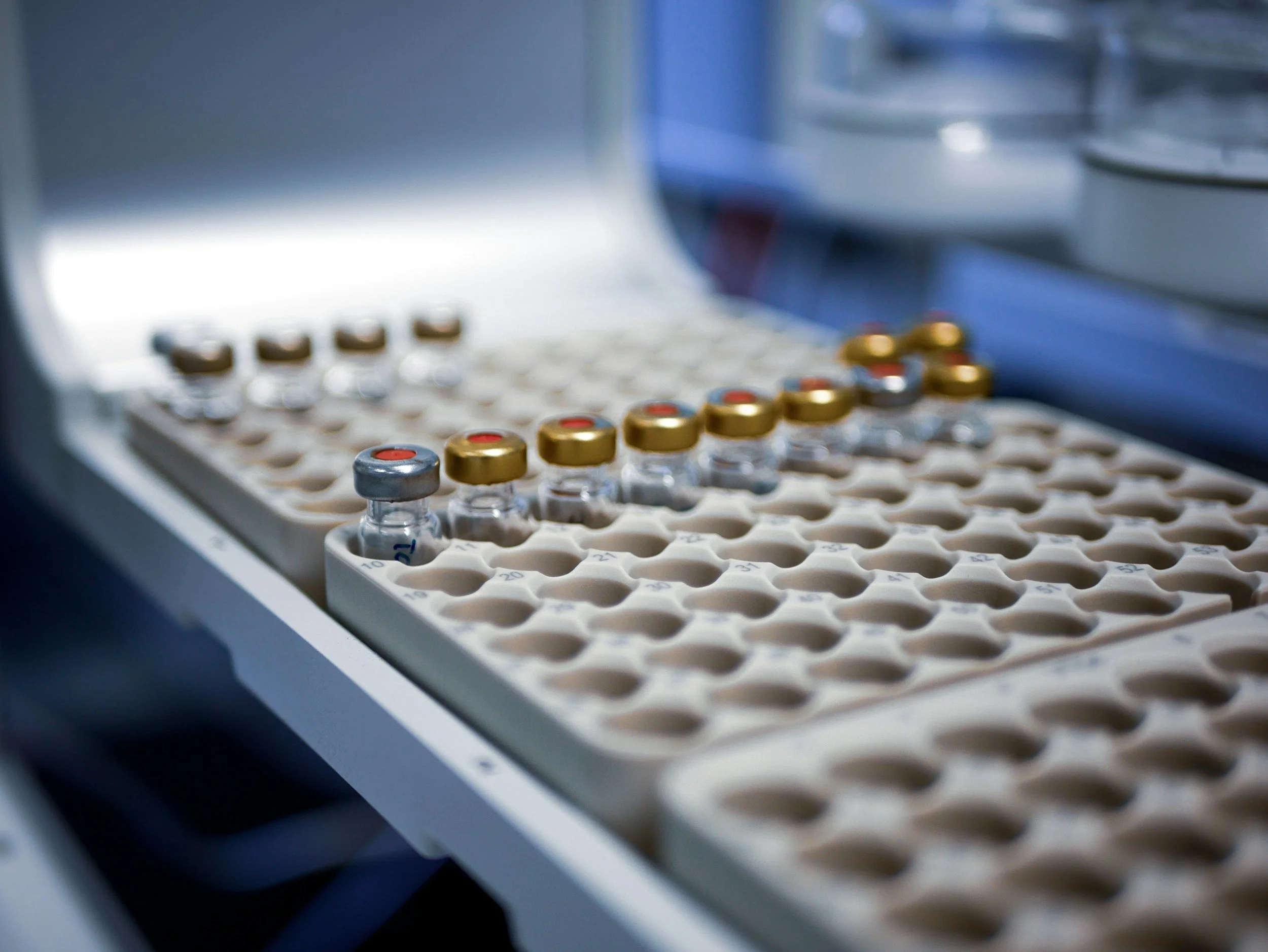 Vials with red caps in an organized tray, likely in a laboratory or medical setting.