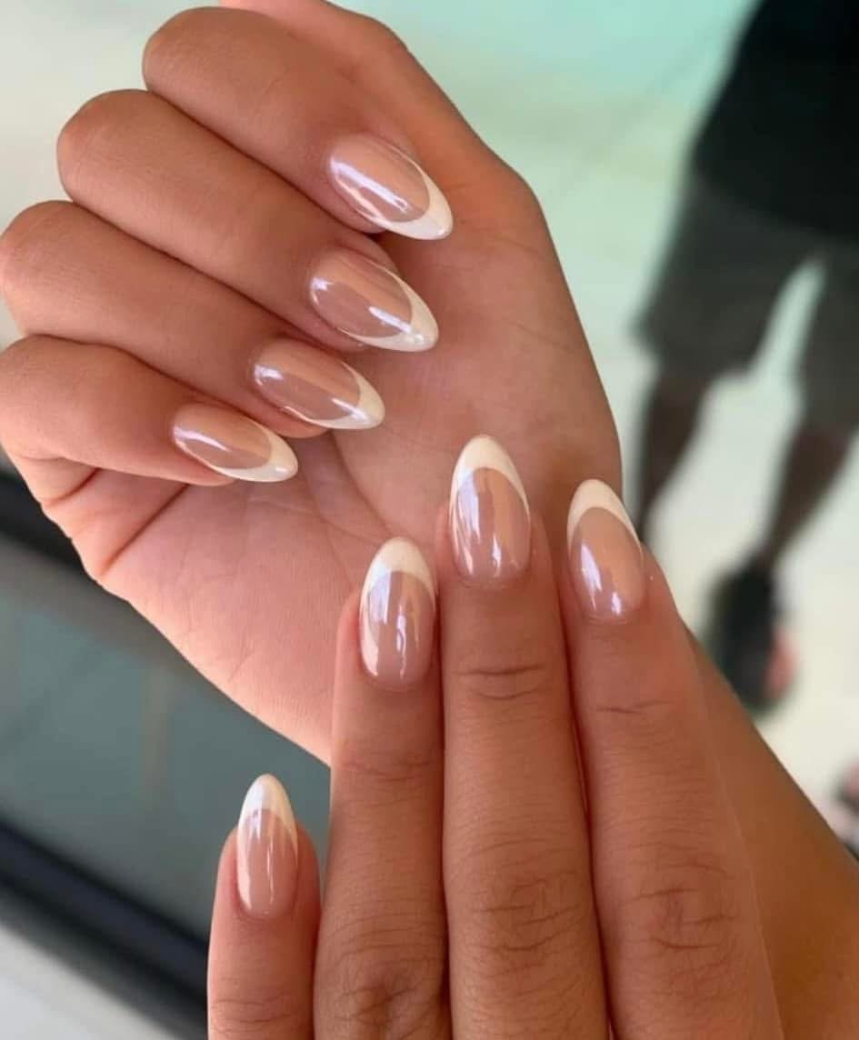 Close-up of hands with neatly manicured nails featuring a French tip design, with a natural base and white tips.
