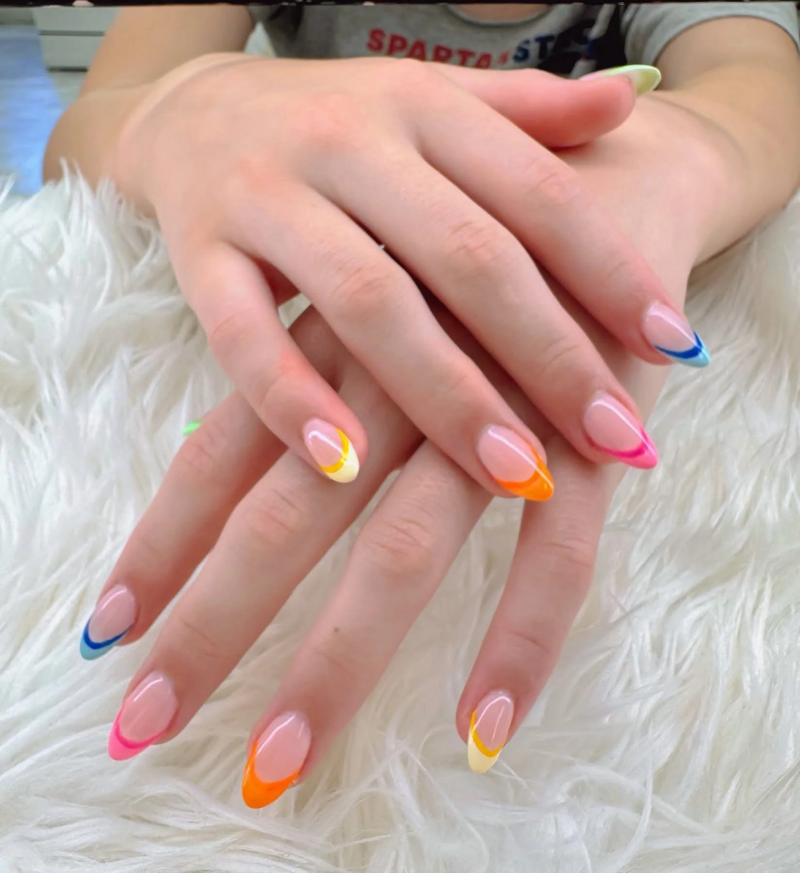Close-up of a customer's hands with colorful nail art on a white fluffy surface.