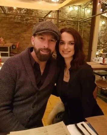 Man and woman sitting together at a restaurant or cafe, smiling at the camera.