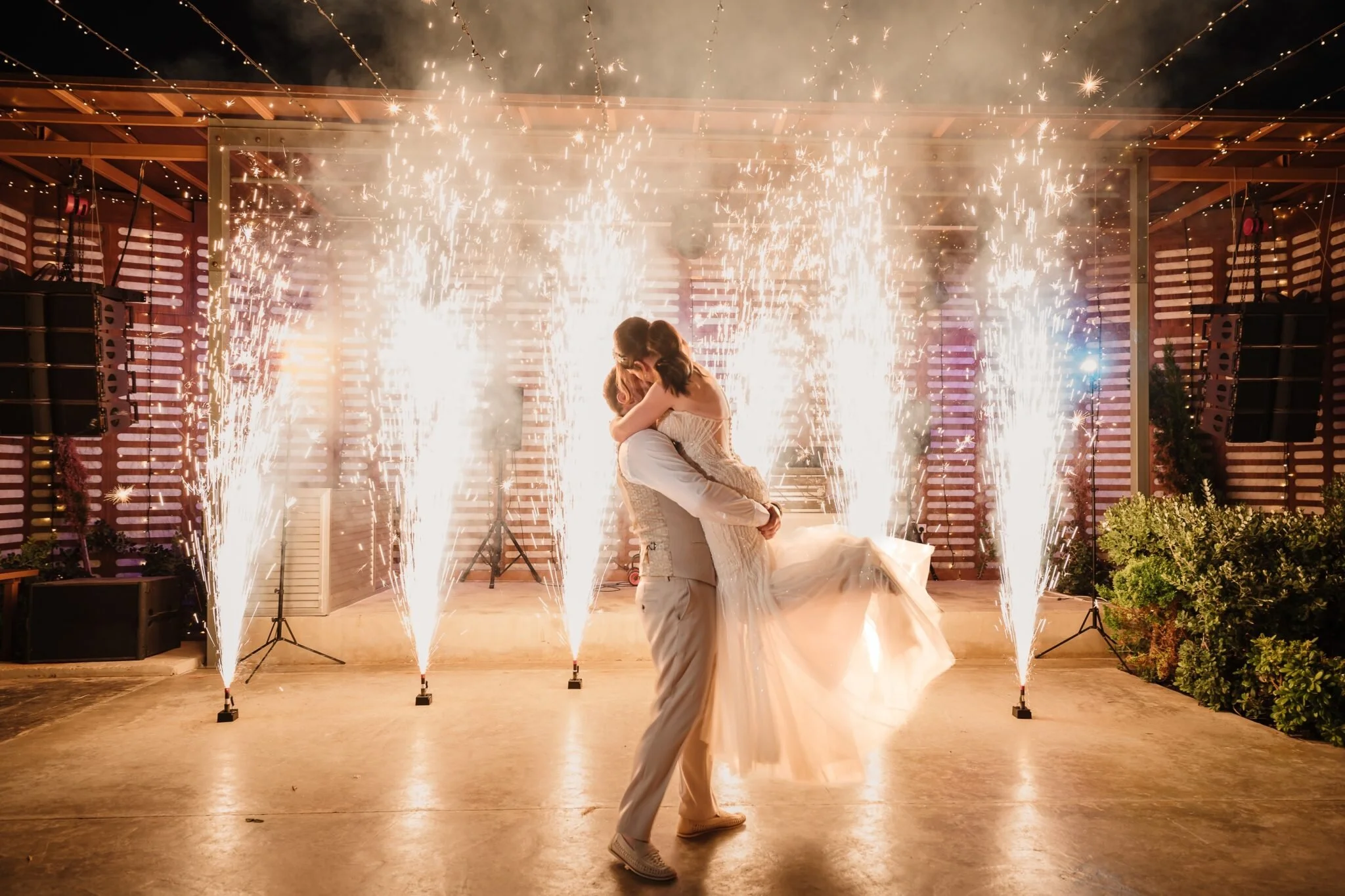 A newlywed couple dancing surrounded by fireworks at a wedding reception.