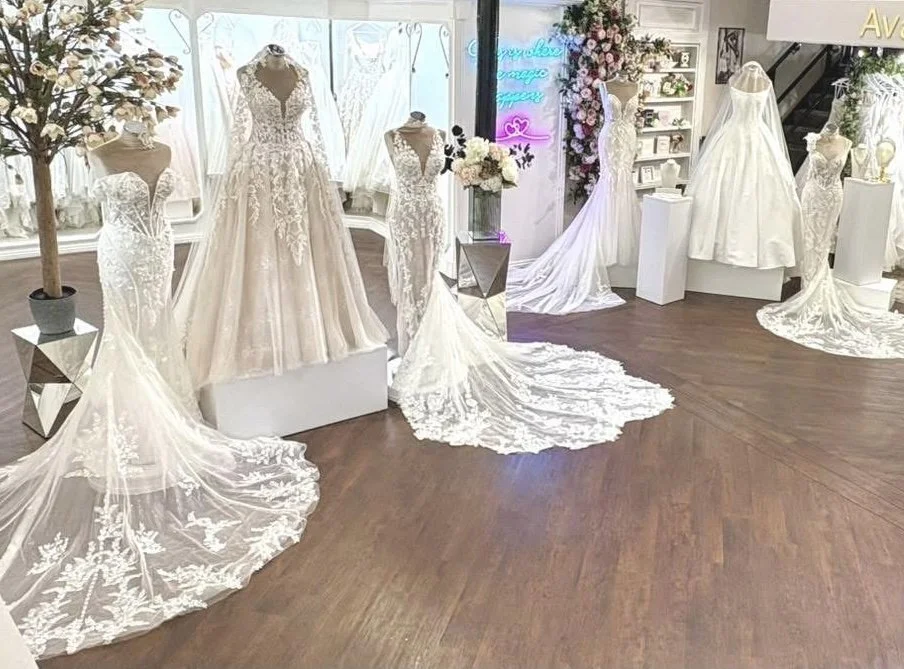 Display of white wedding dresses with lace and satin fabrics in a bridal store.