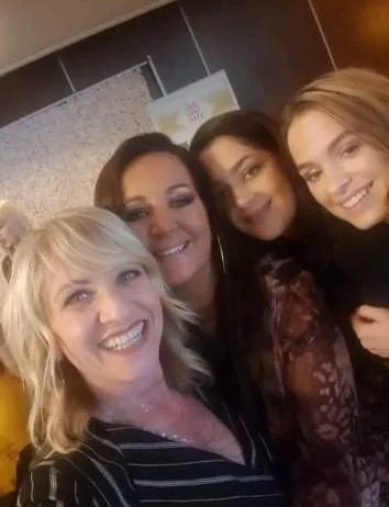 Four women smiling and posing for a photo together indoors.