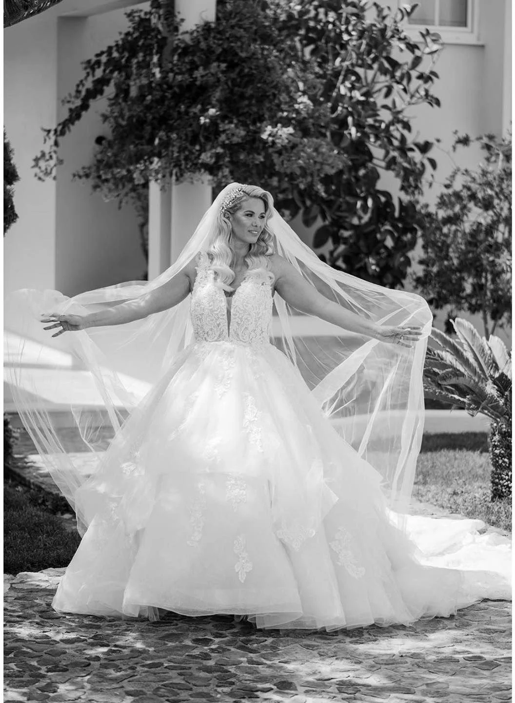 A woman in a wedding gown holding a veil outdoors