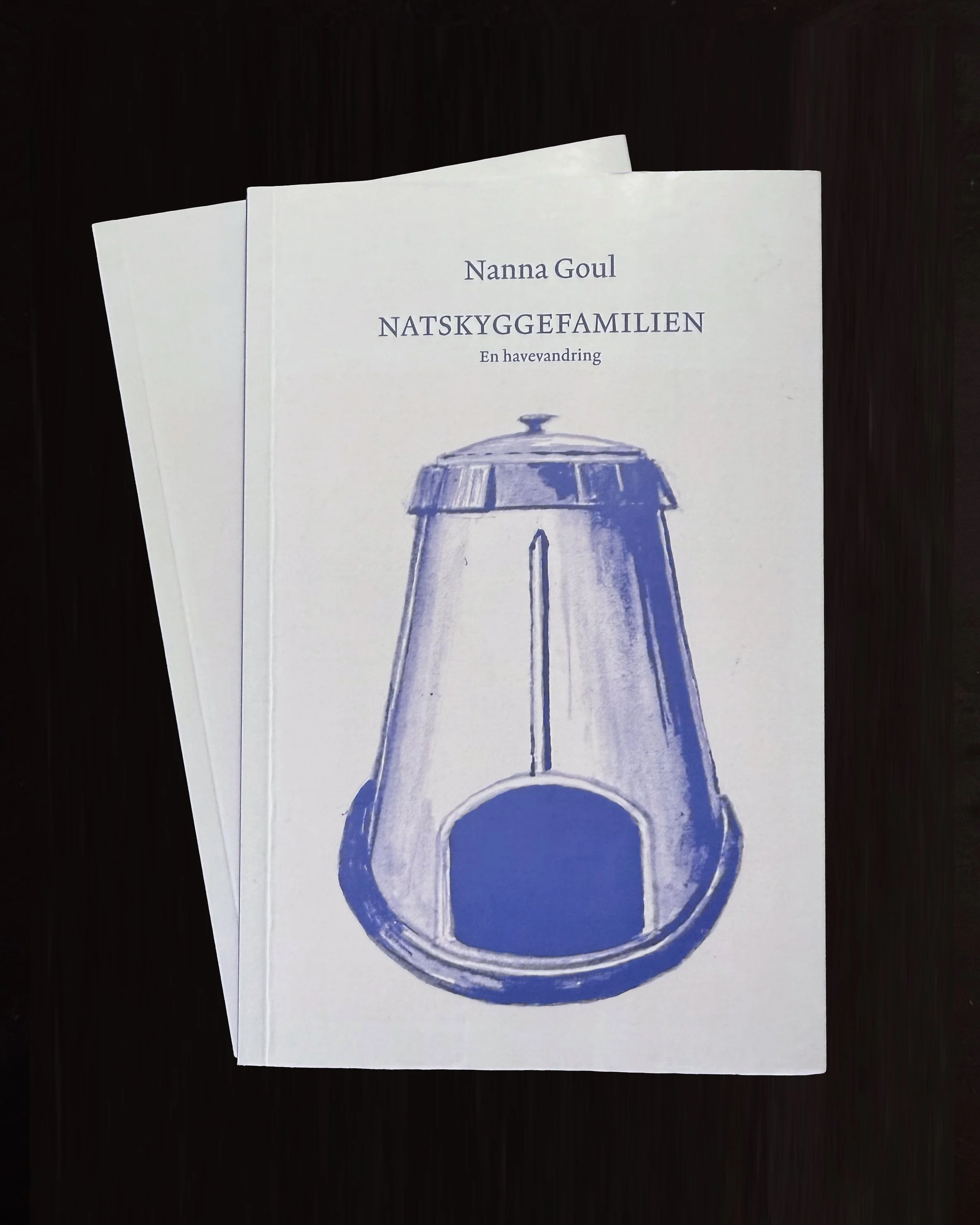 A book with a white cover displaying a blue illustration of a lighthouse and Norwegian text.