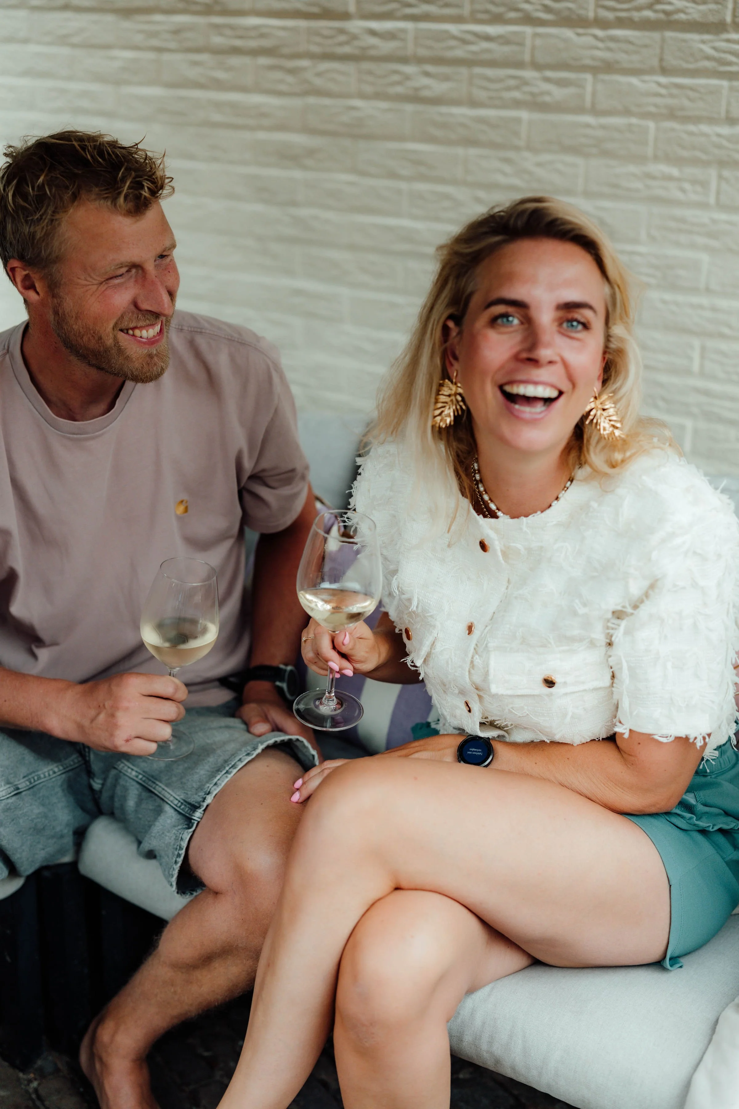 Vader en bonusmoeder mensen die samen op een bank zitten, lachen en wijn drinken.