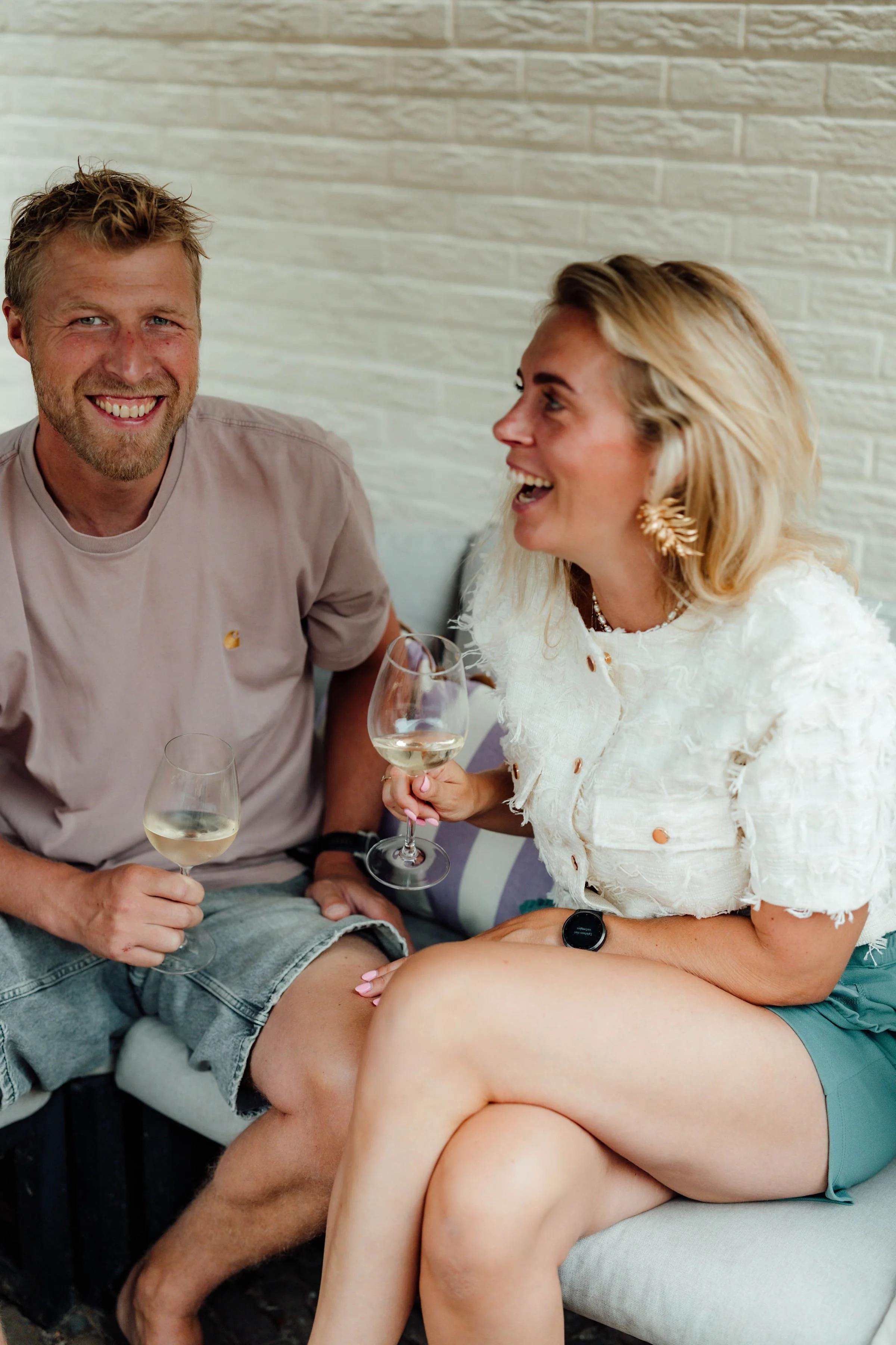Vader en bonusmoeder lachen en klinken met witte wijn in een gezellige setting binnen hun samengestelde gezin.
