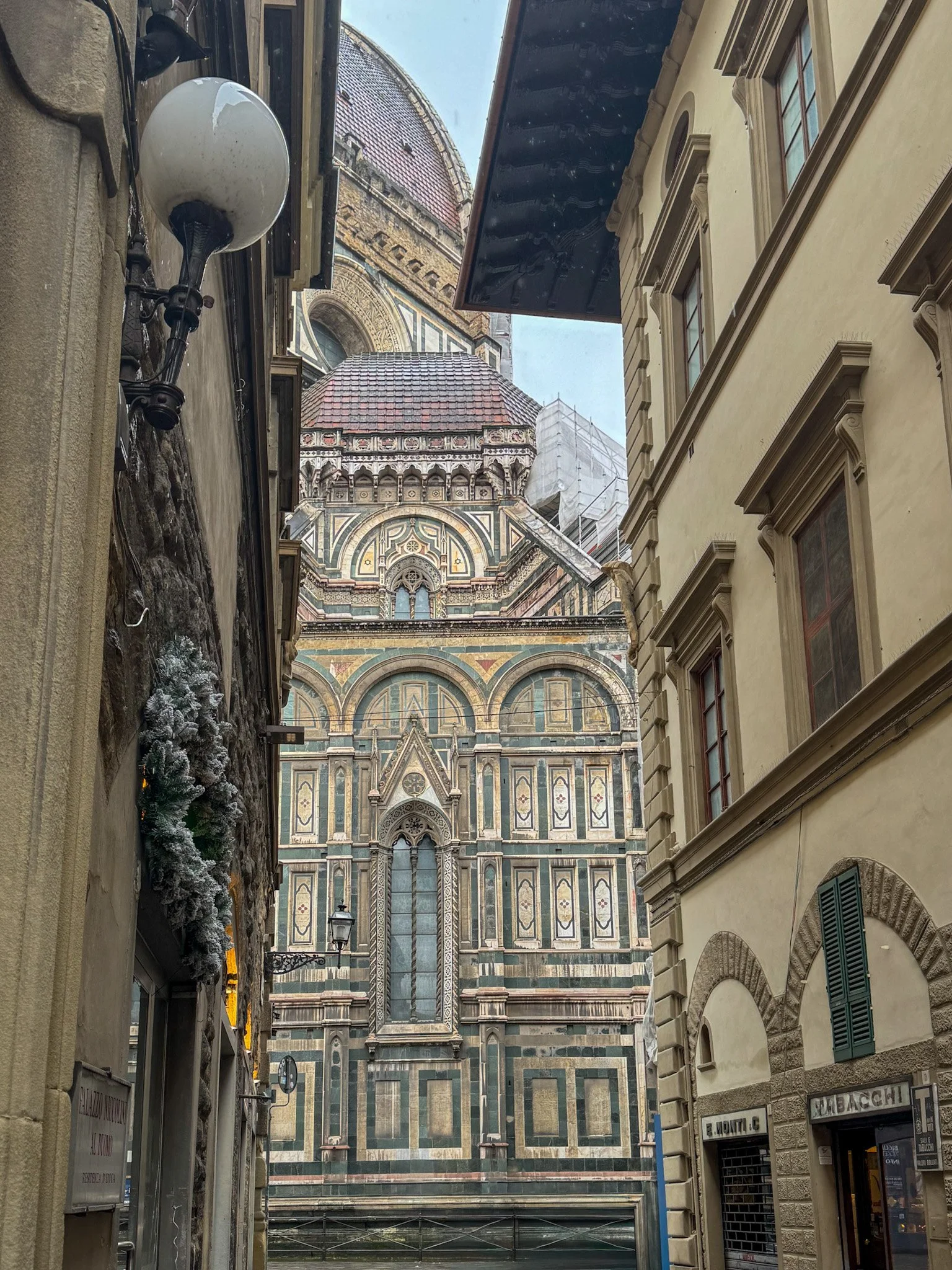 Narrow Florentine street revealing Florence Cathedral façade near historic palace entrance, Palazzo Niccolini al Duomo – Florence, Italy.